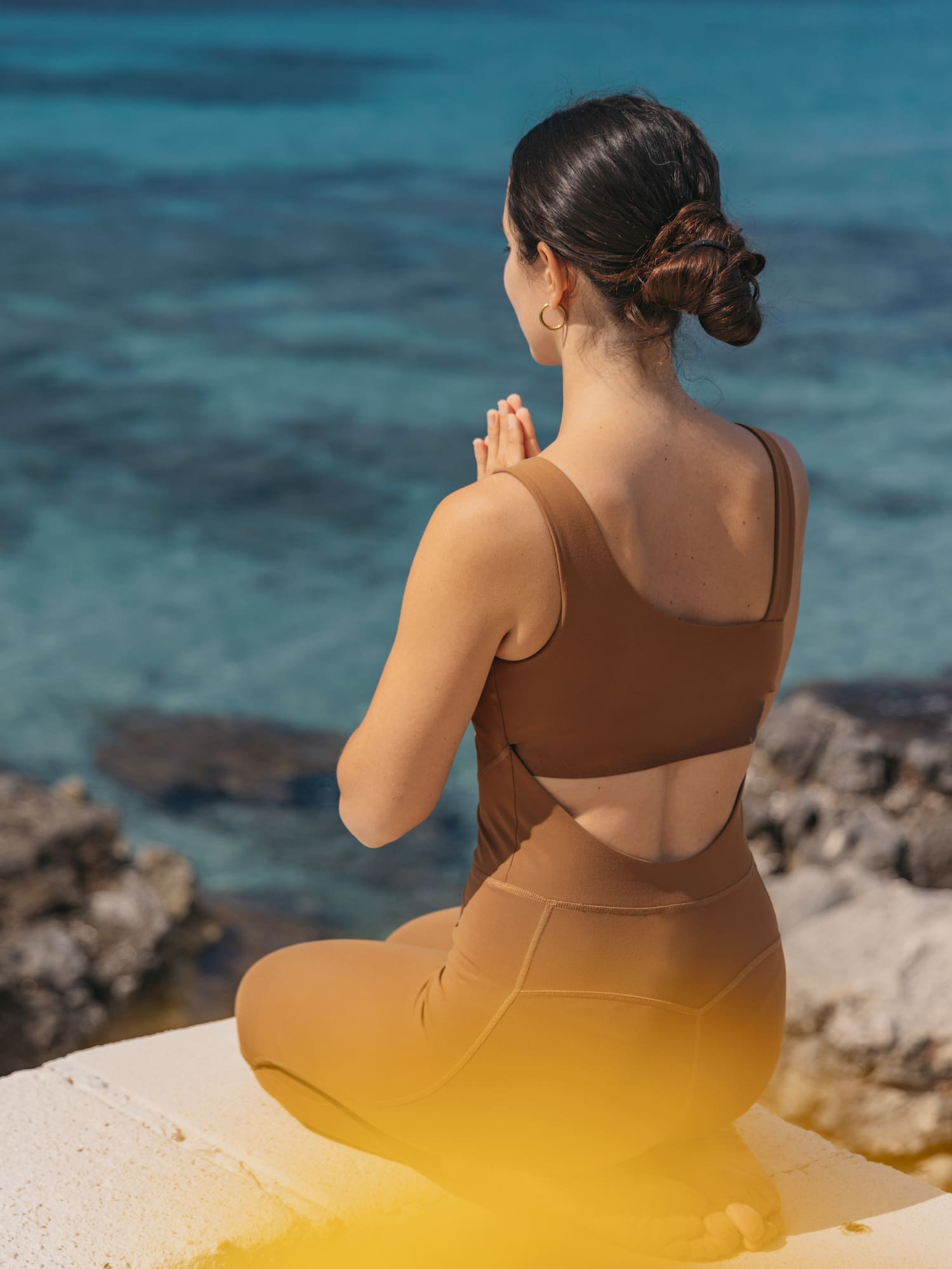 a woman sitting on a ledge with her hands together