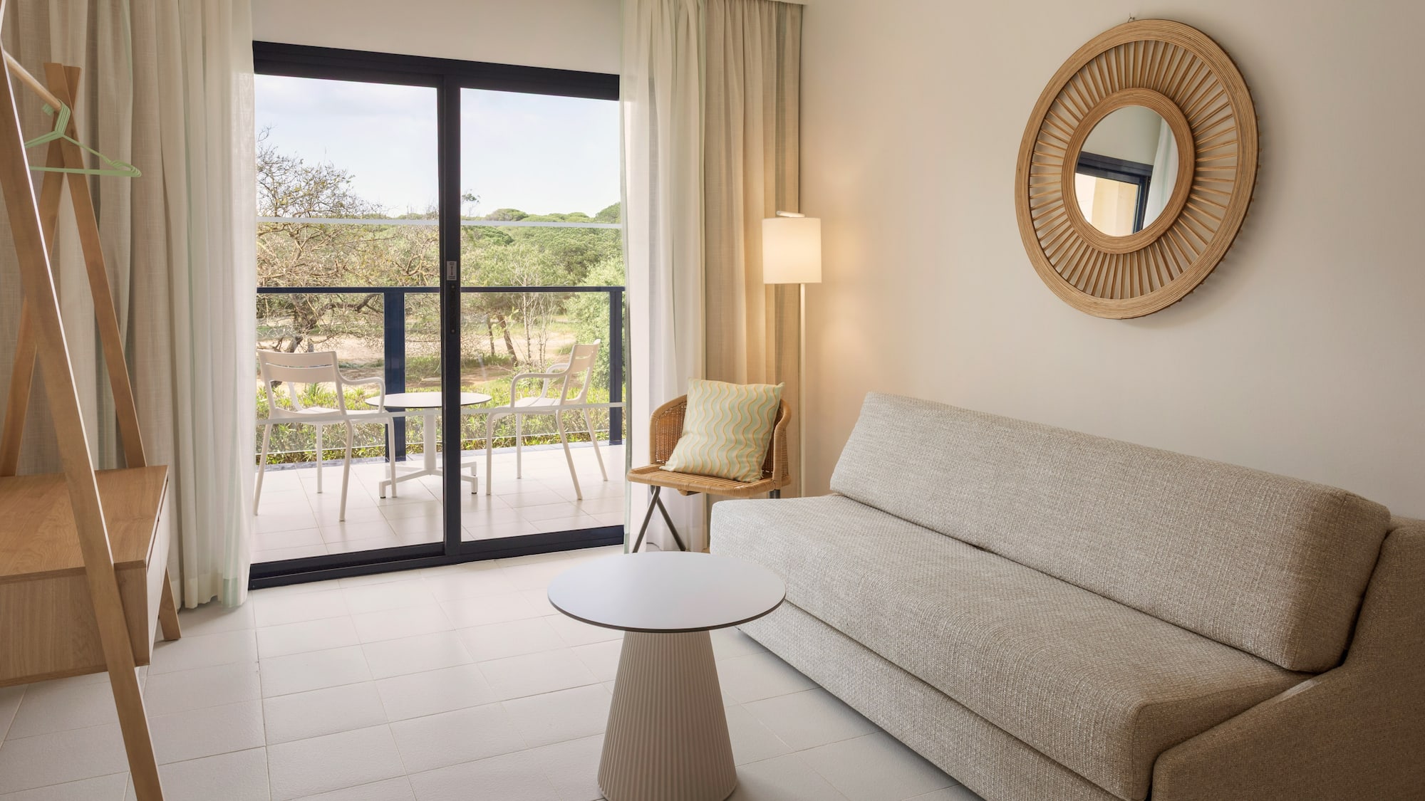 Bright modern hotel suite living room with balcony and natural view.