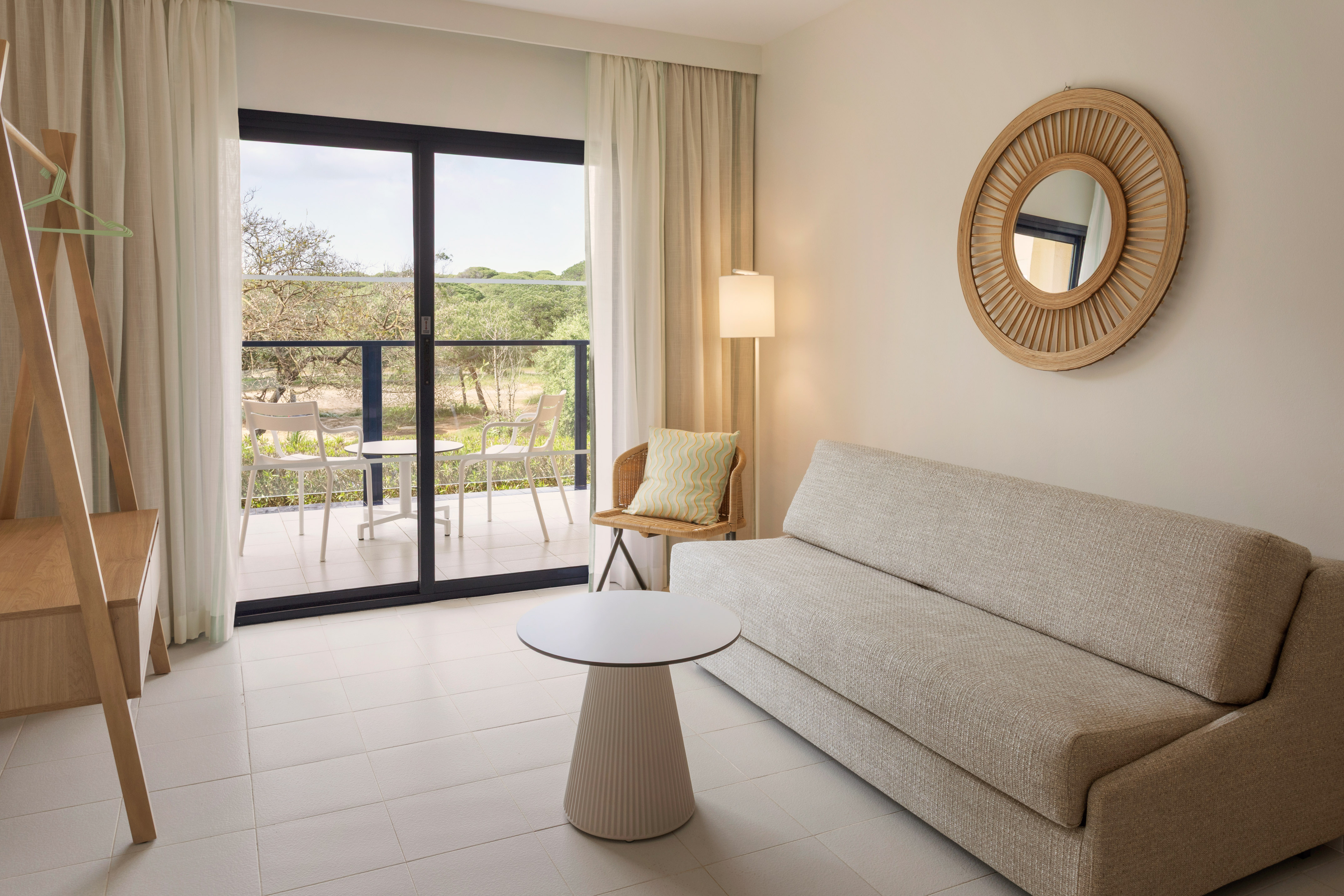 Bright modern hotel suite living room with balcony and natural view.