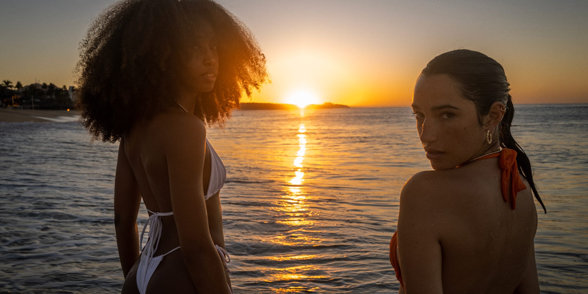 two women in garments standing in front of water