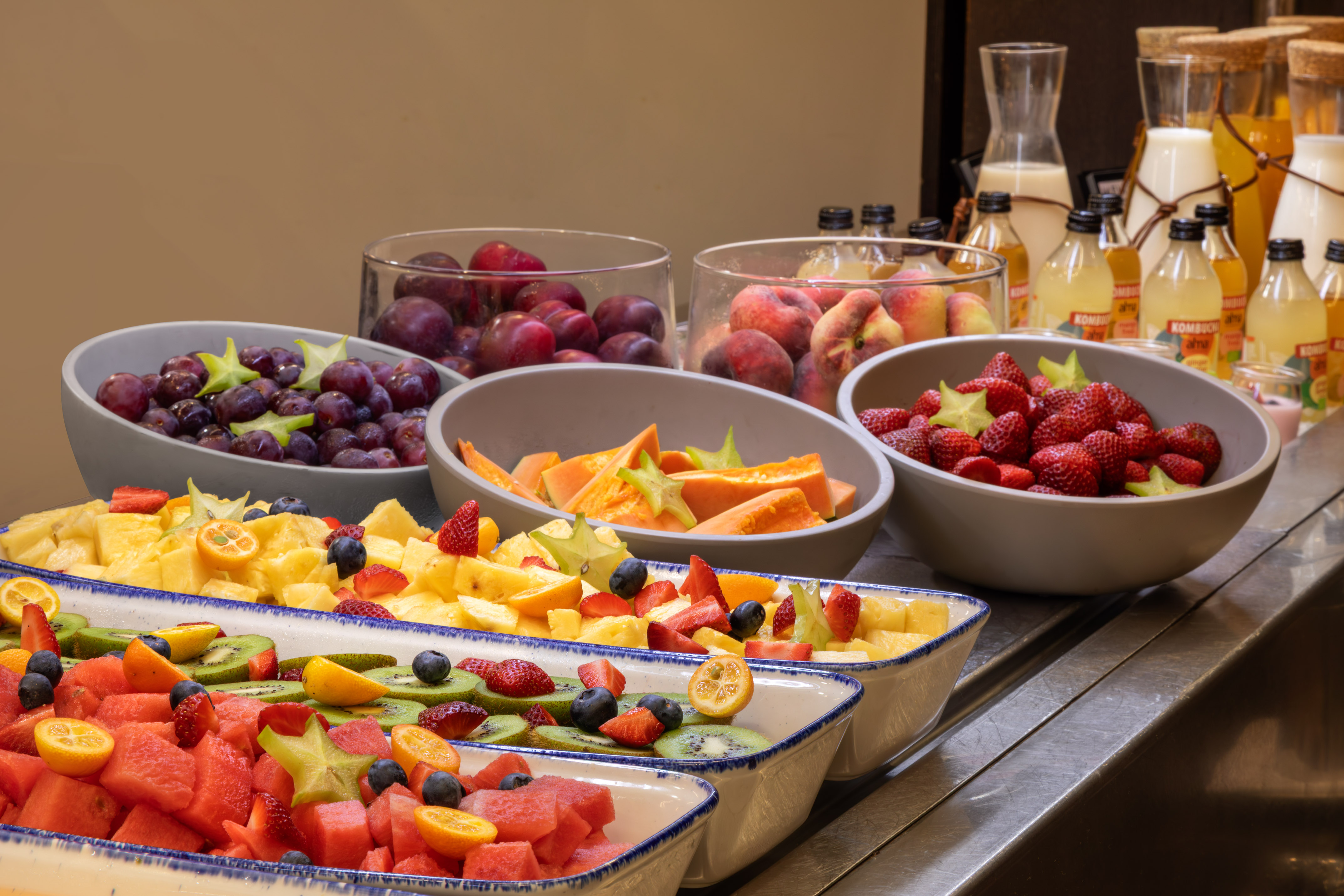 Colorful fresh fruit buffet with watermelon, kiwi, berries, and kombucha.