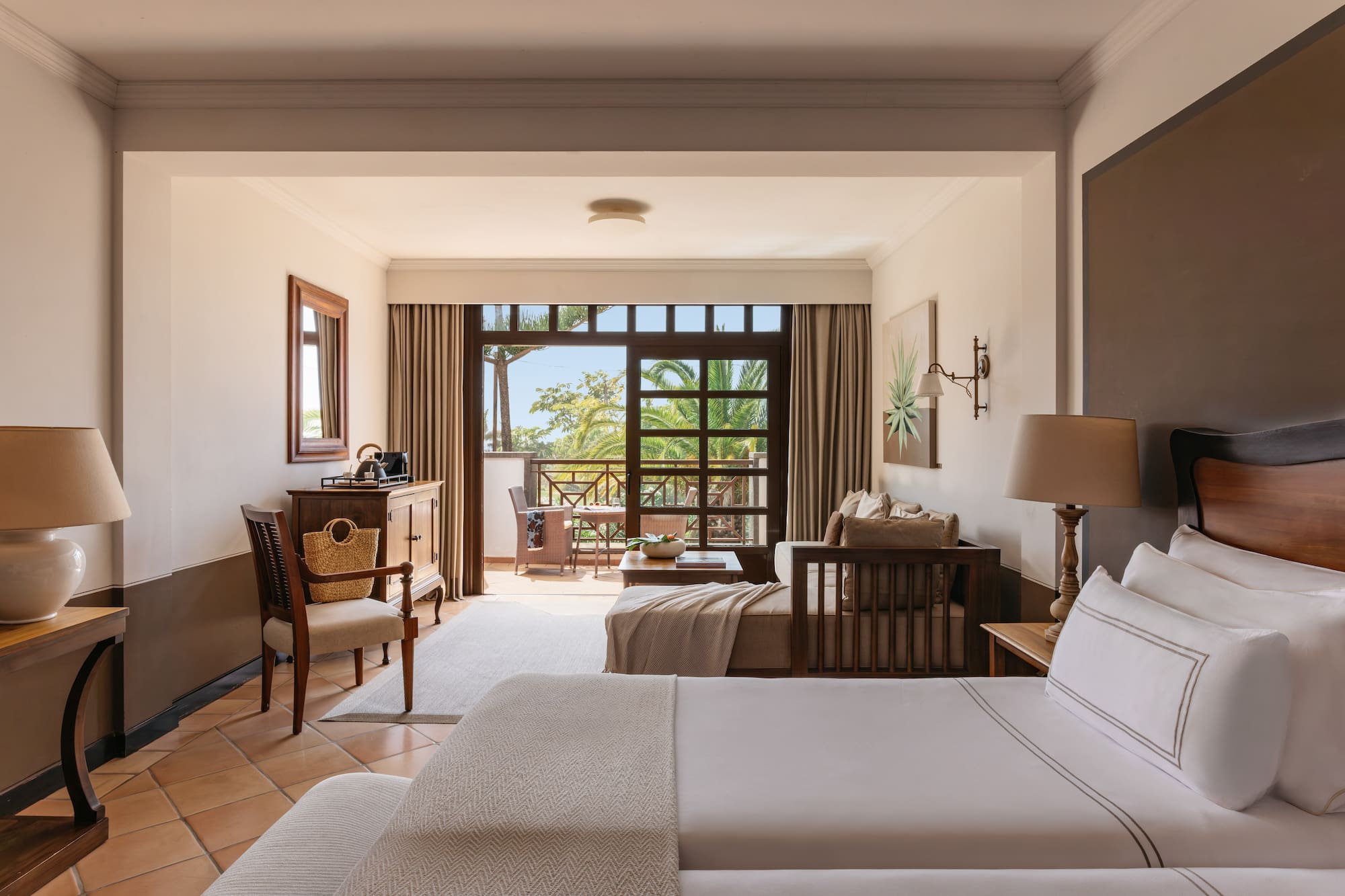 Tropical resort bedroom with private balcony and lush palm views.
