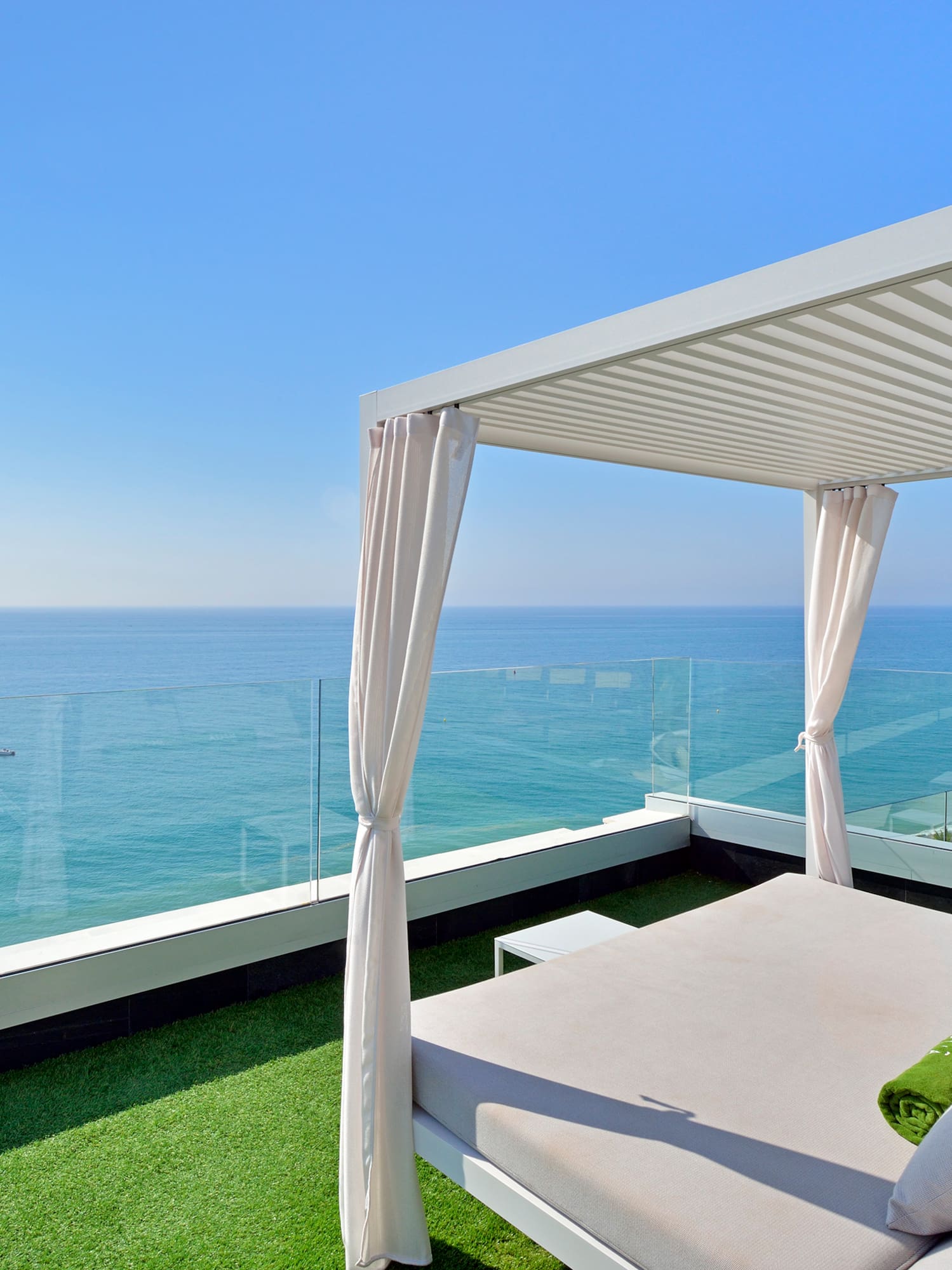 a bed on a balcony overlooking the ocean