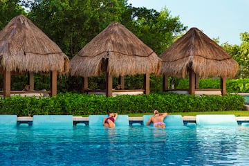 people in a pool with straw umbrellas