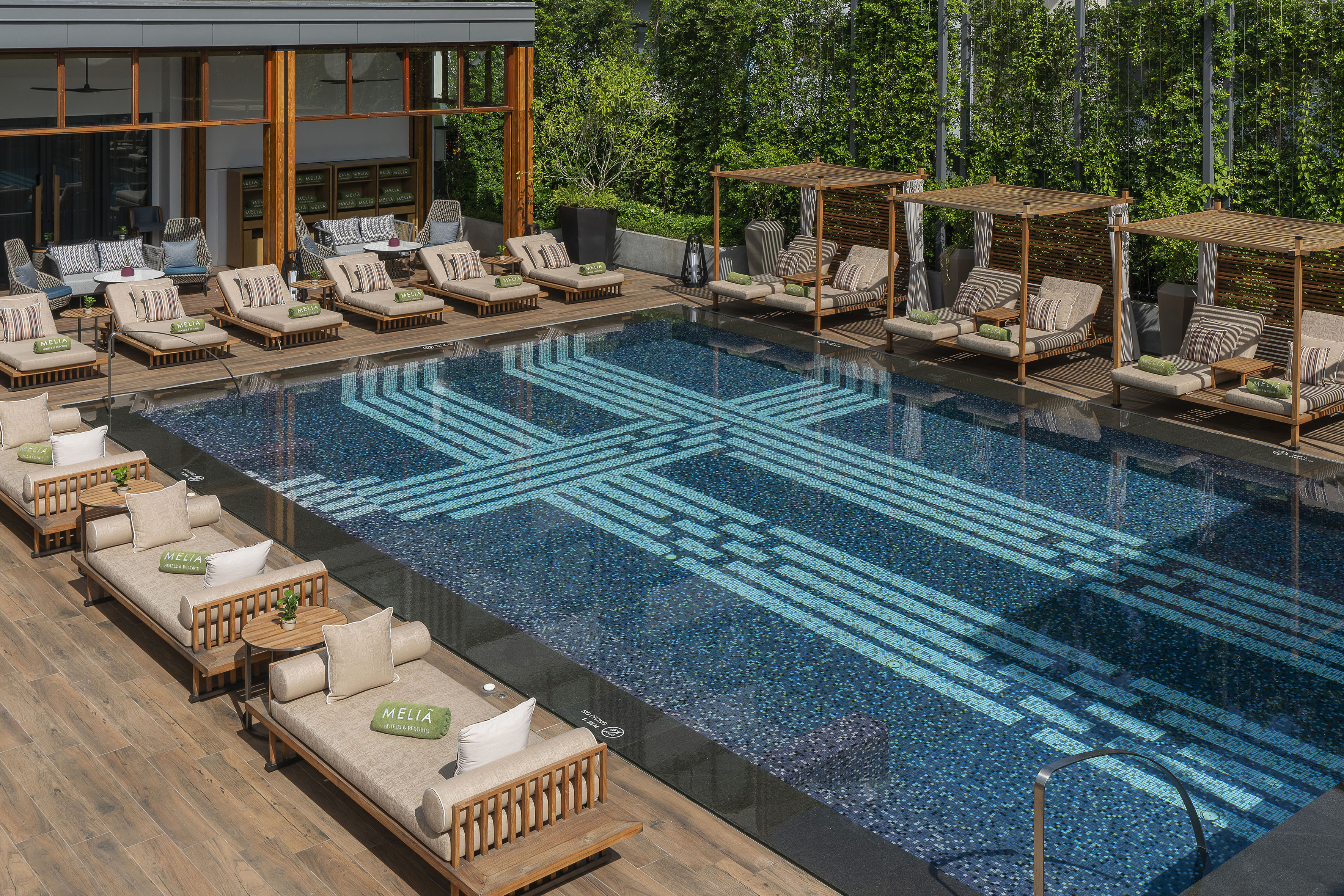 Meliá luxury pool deck, patterned swimming pool, lounge chairs, and daybeds.