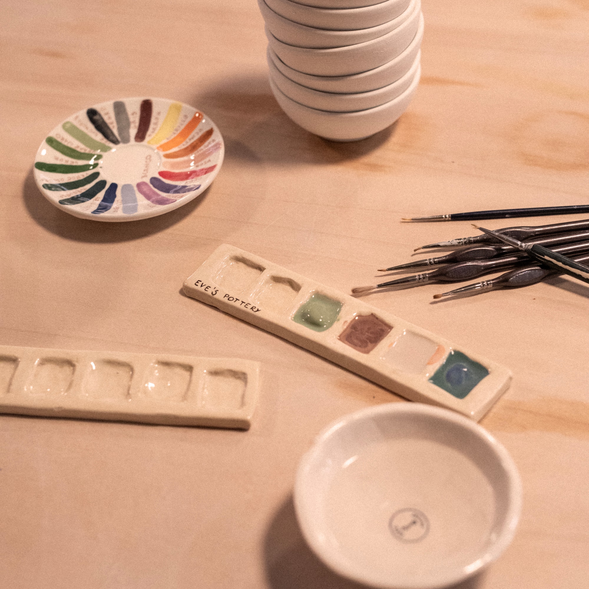 a stack of plates and paint brushes on a table