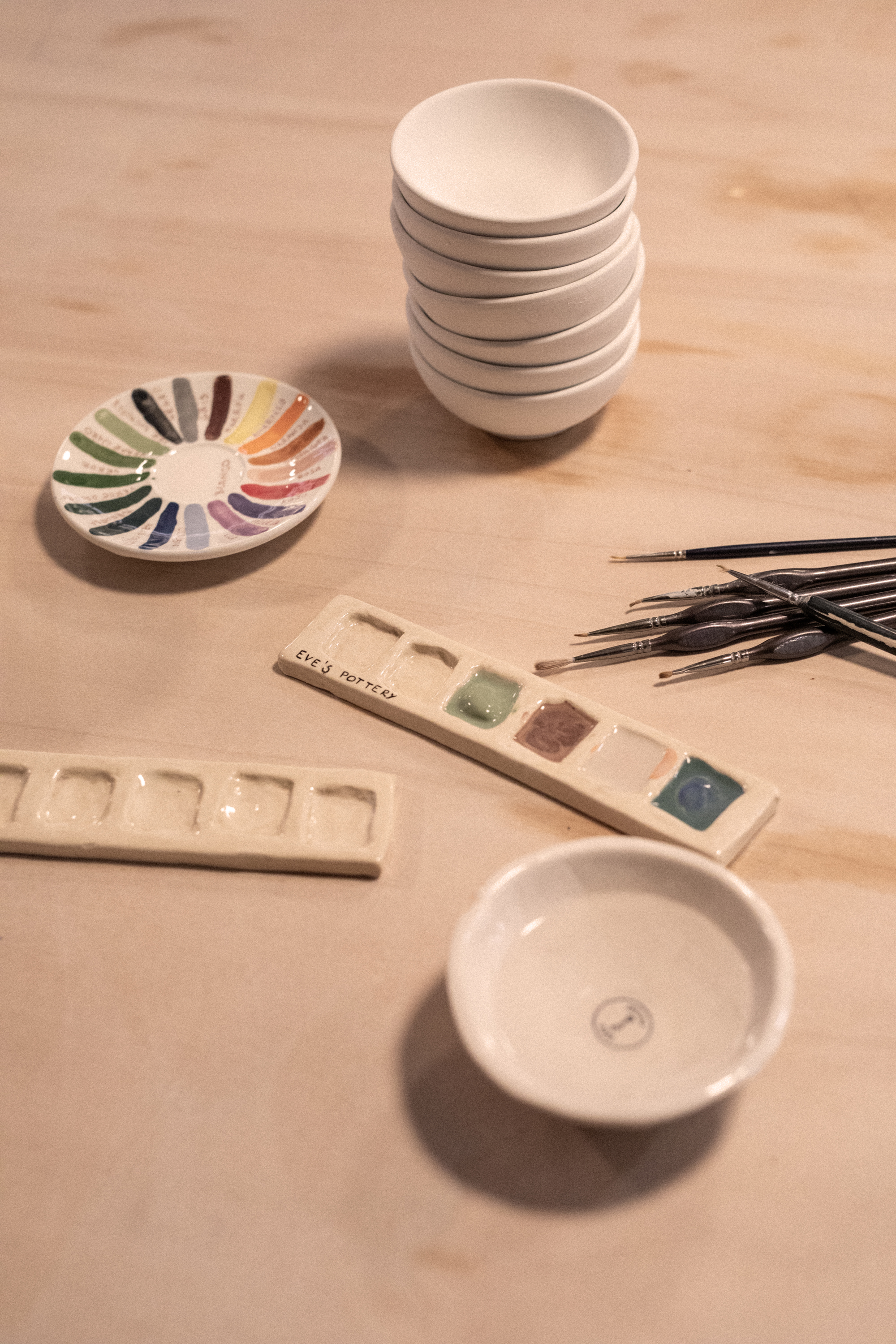 a stack of plates and paint brushes on a table