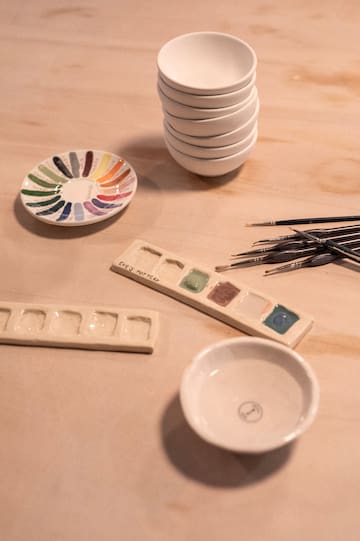 a stack of plates and paint brushes on a table
