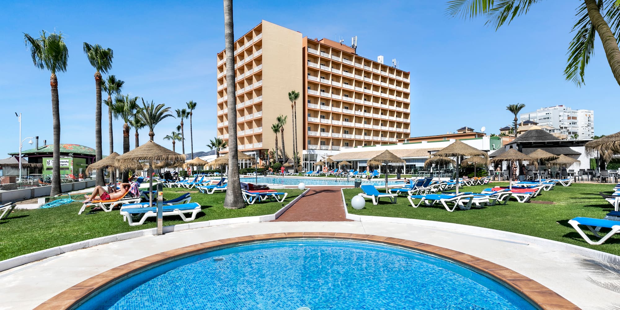 a pool with lounge chairs and umbrellas in front of a building