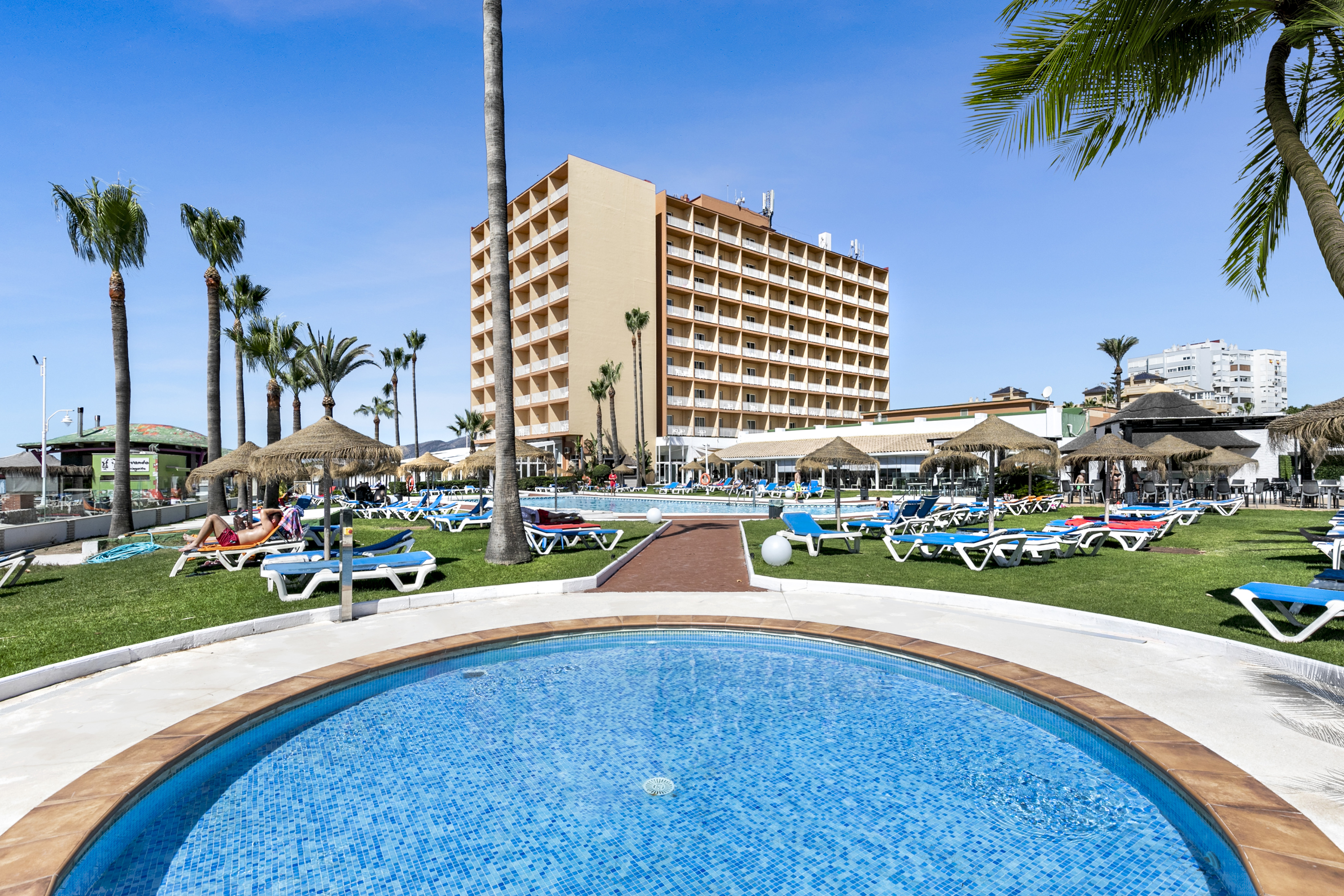 a pool with lounge chairs and umbrellas in front of a building