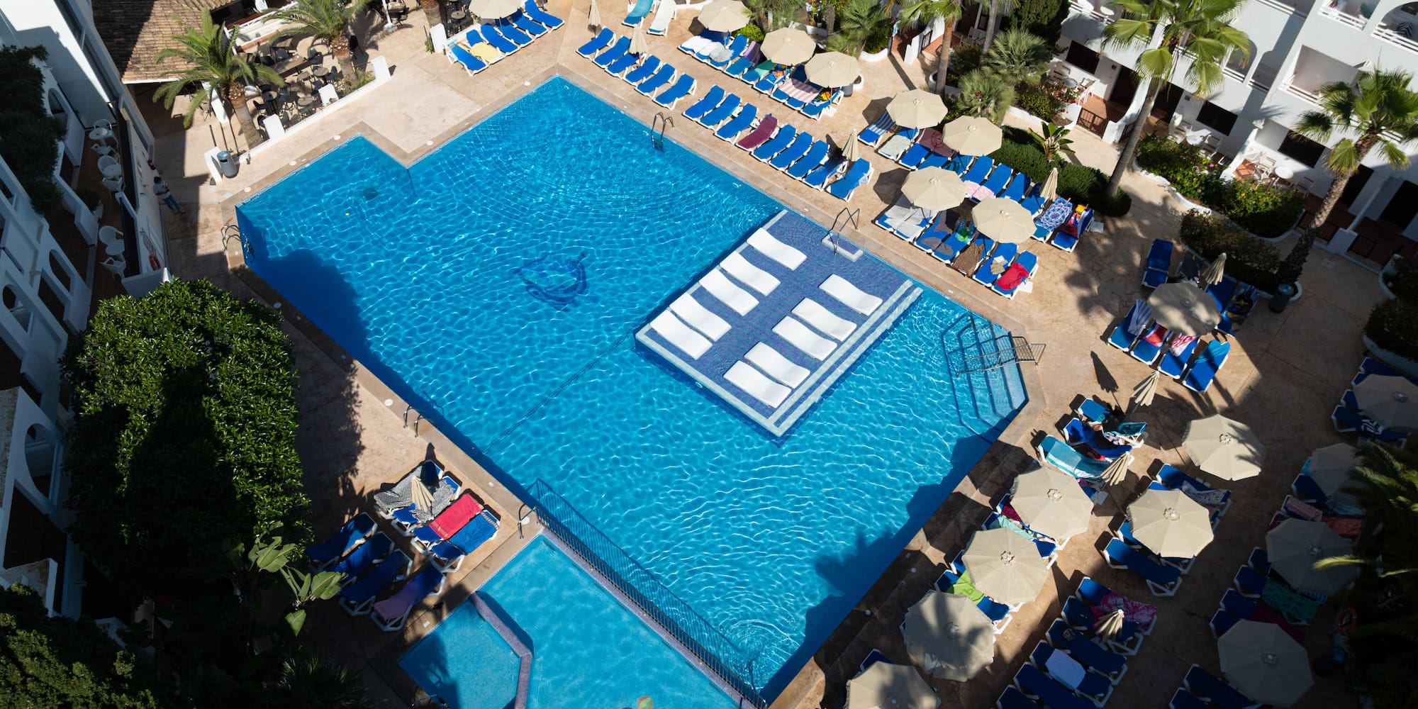 a swimming pool with lounge chairs and umbrellas