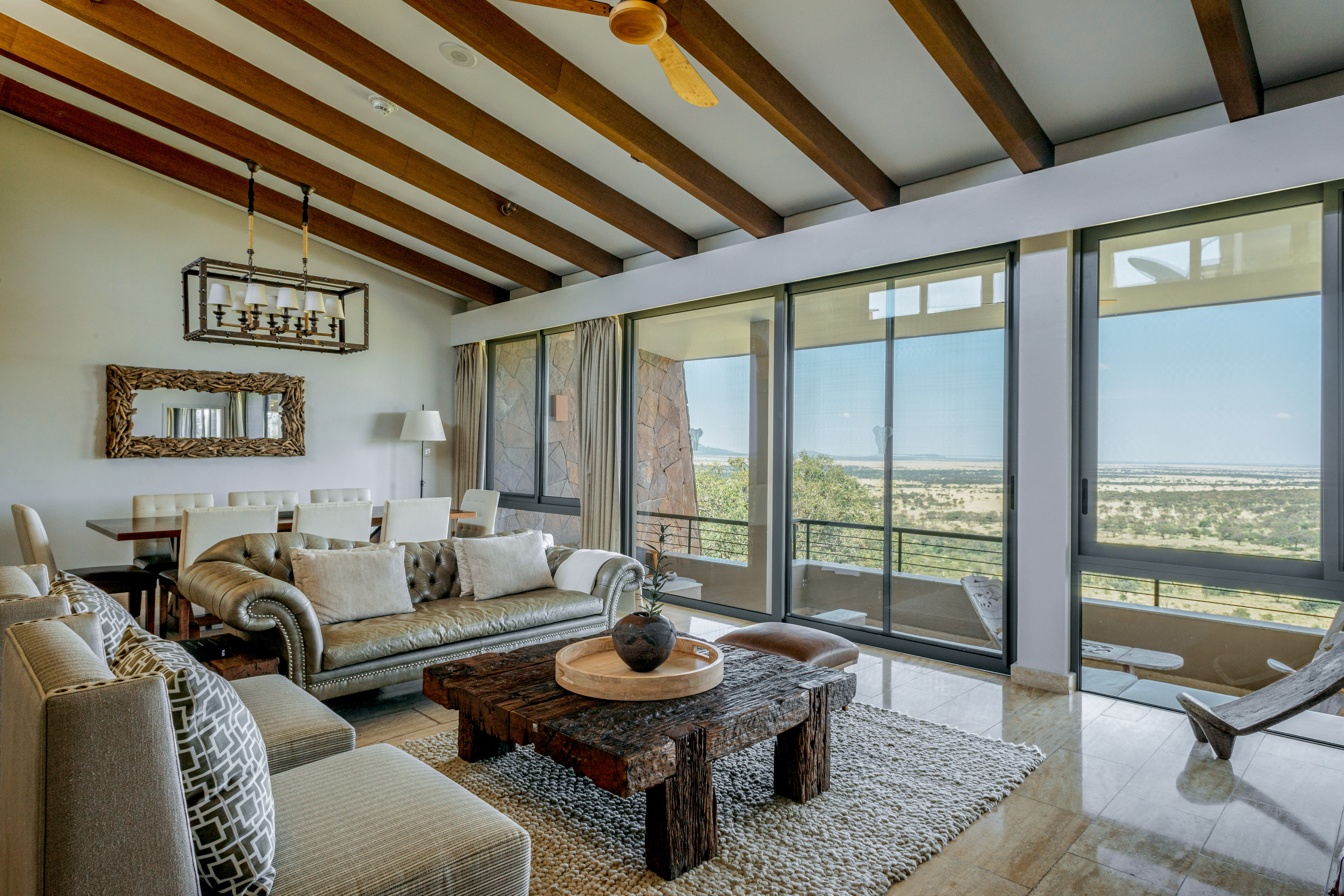 Safari lodge living room with panoramic savanna views and rustic decor.