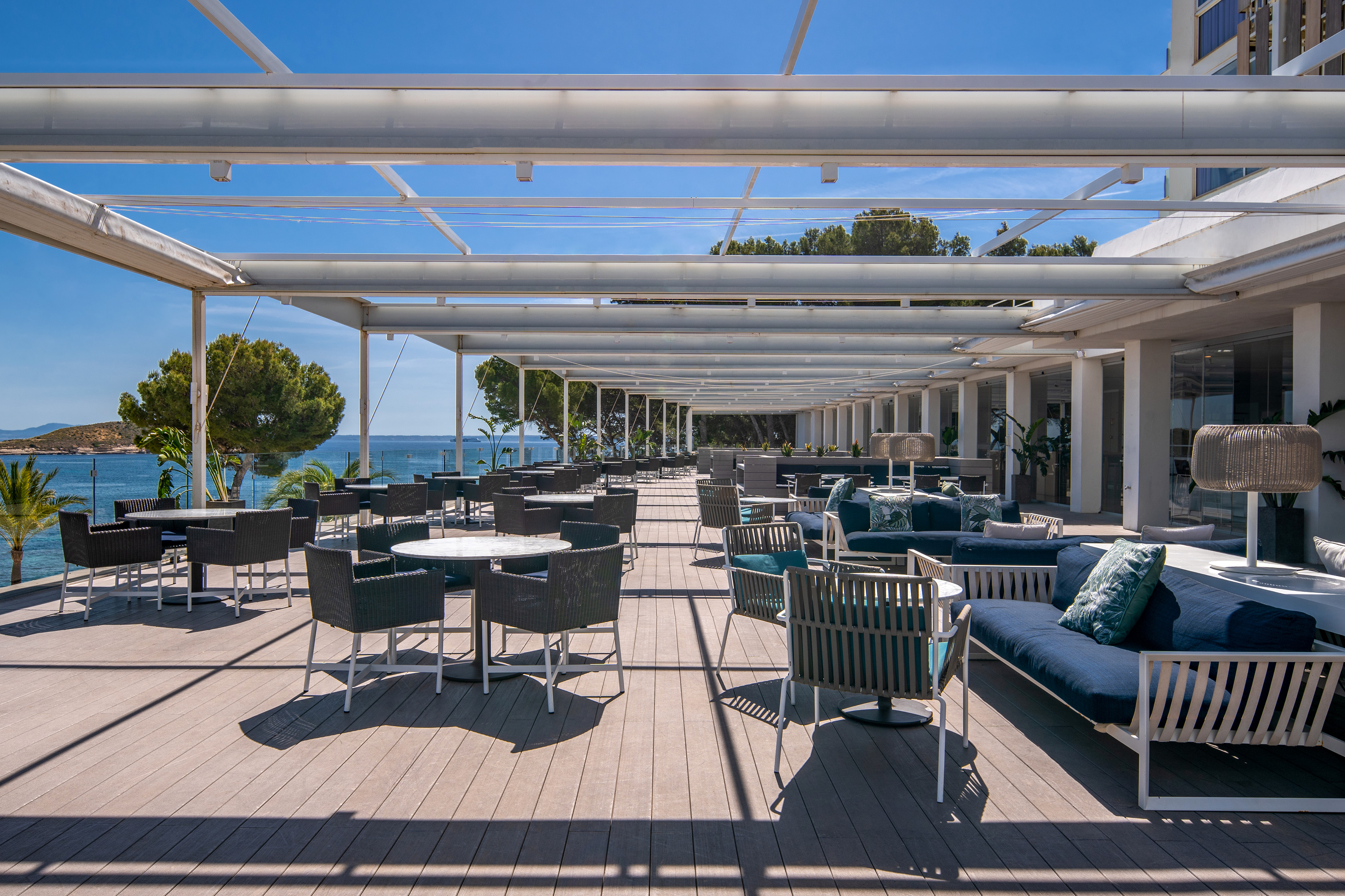 Spacious outdoor resort terrace with lounge seating, dining tables, and sea view.