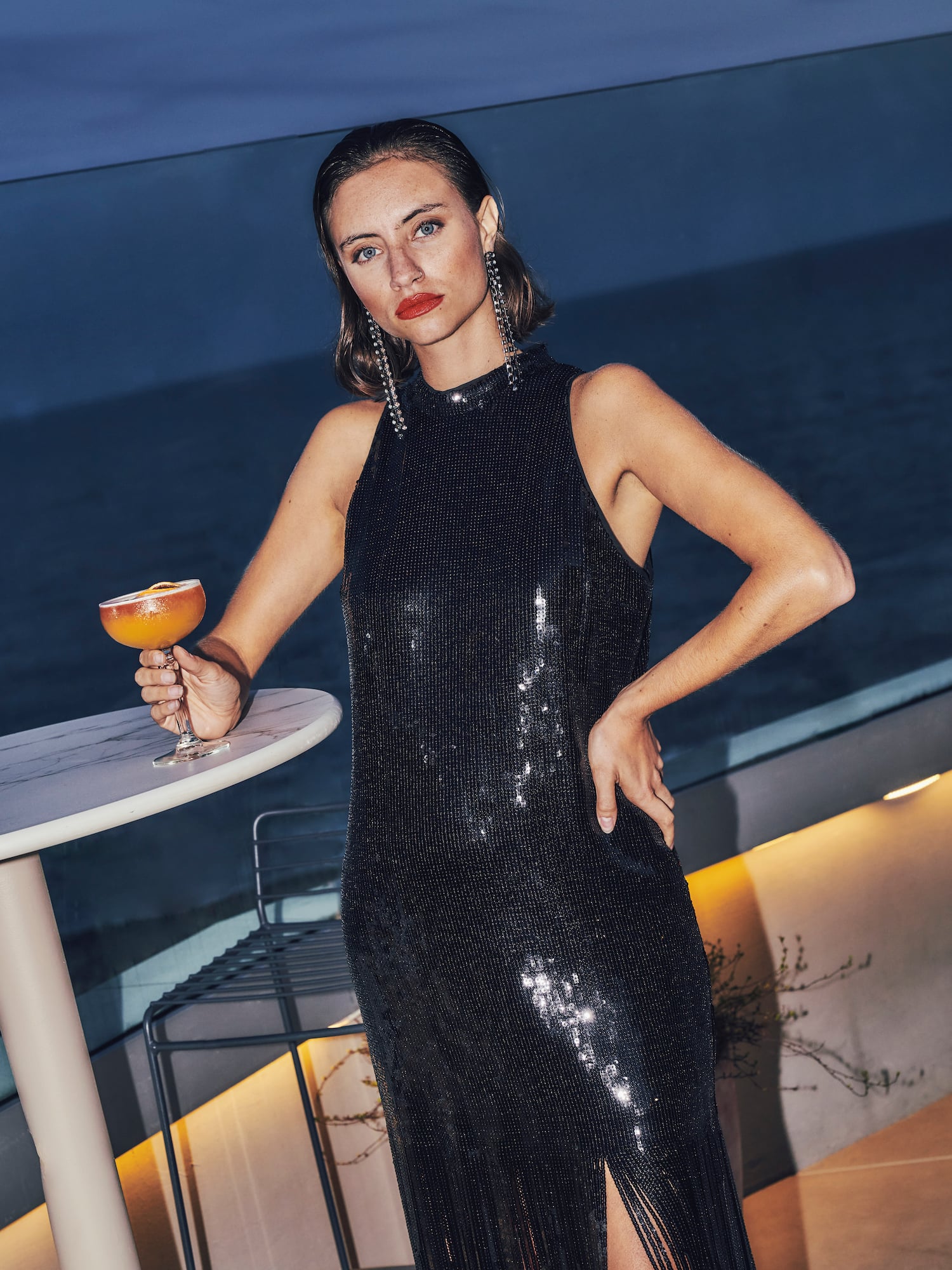 a woman in a black dress holding a drink