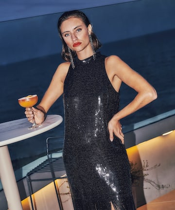 a woman in a black dress holding a drink