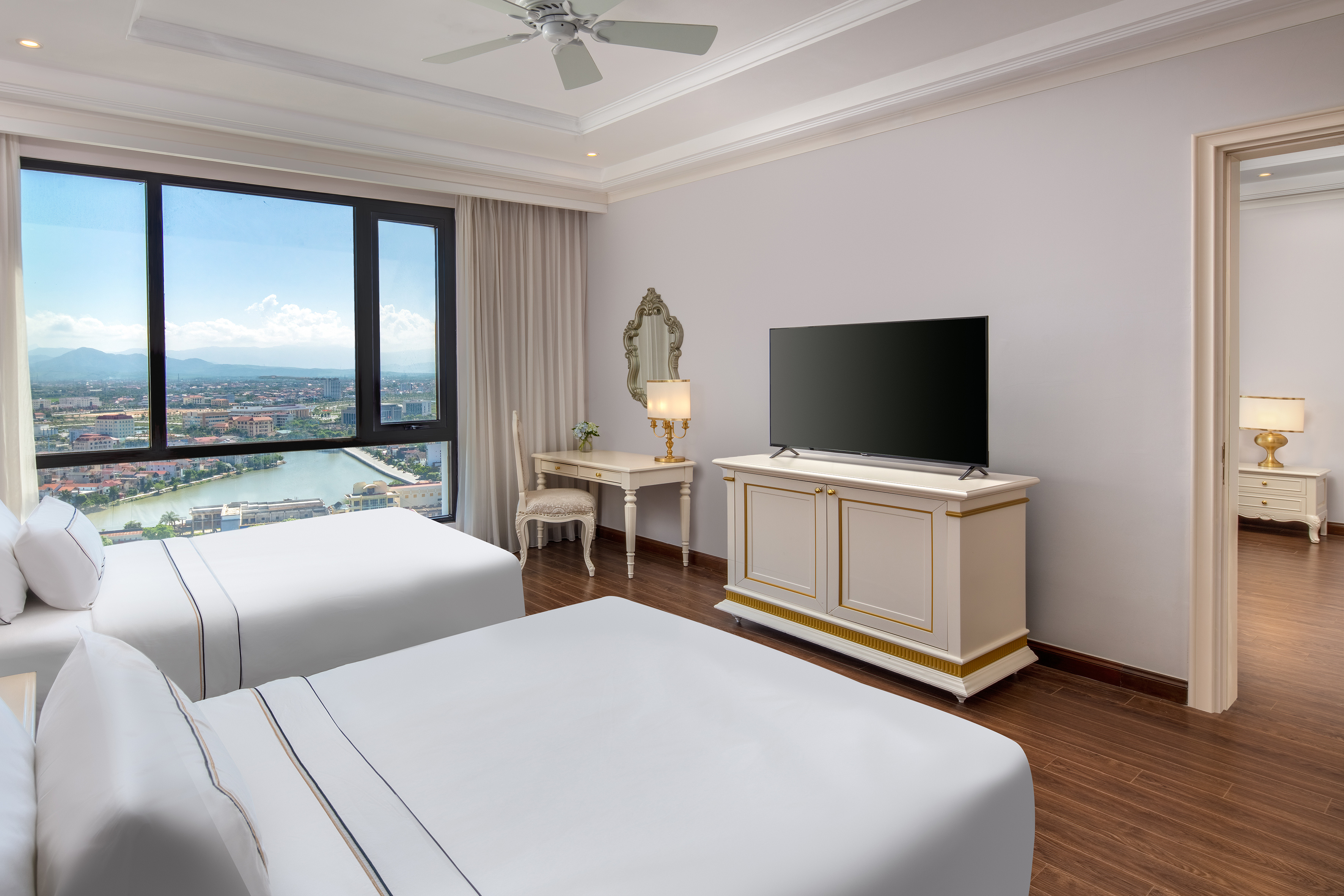 Elegant hotel twin room with expansive city and river view, two beds.