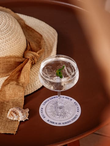 a glass of water with a leaf on top of a white plate