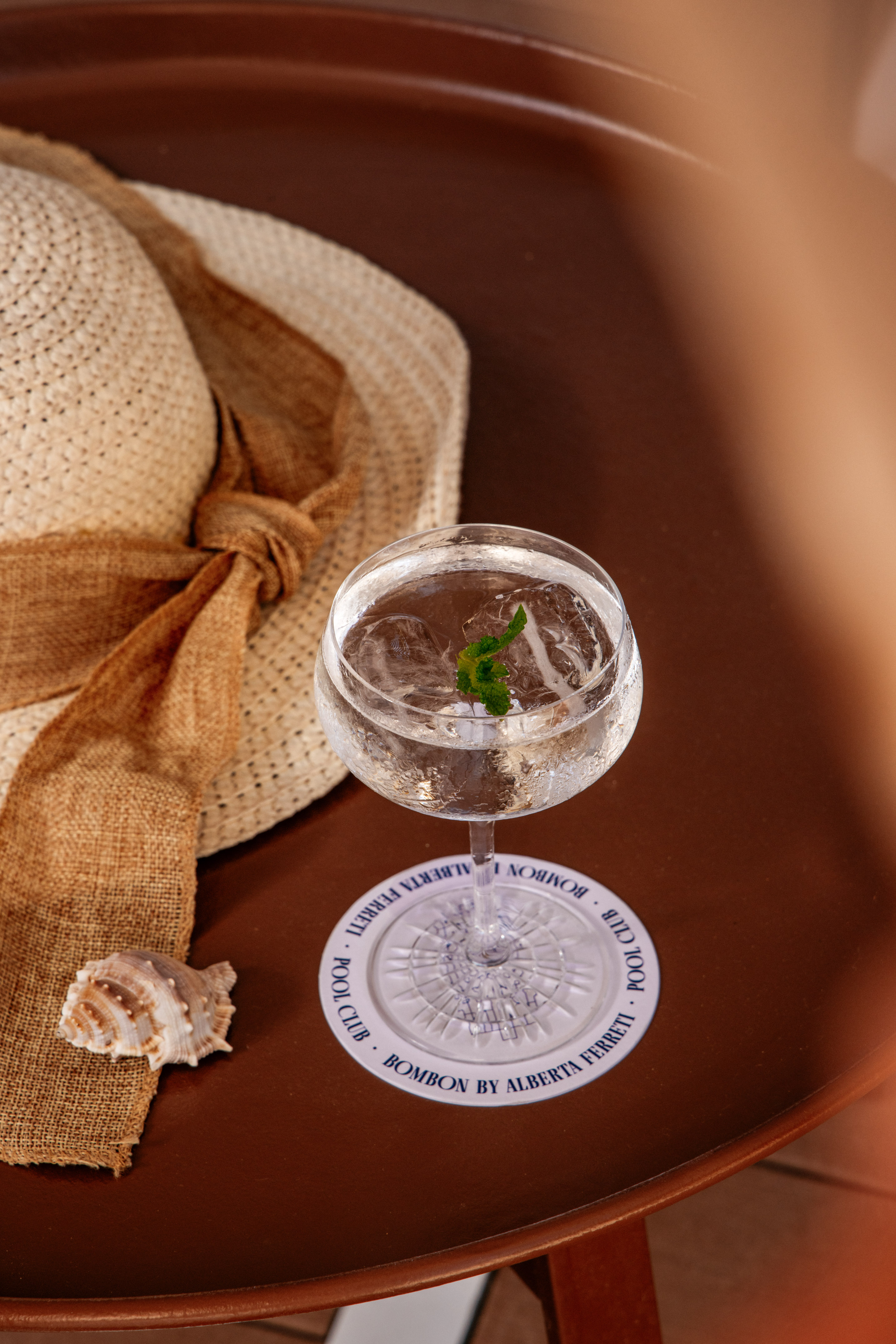 a glass of water with a leaf on top of a white plate