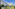 Curved white hotel building with pet park, picnic area, green bushes, and blue sky.