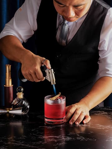 a man holding a lighter and putting a drink into a glass