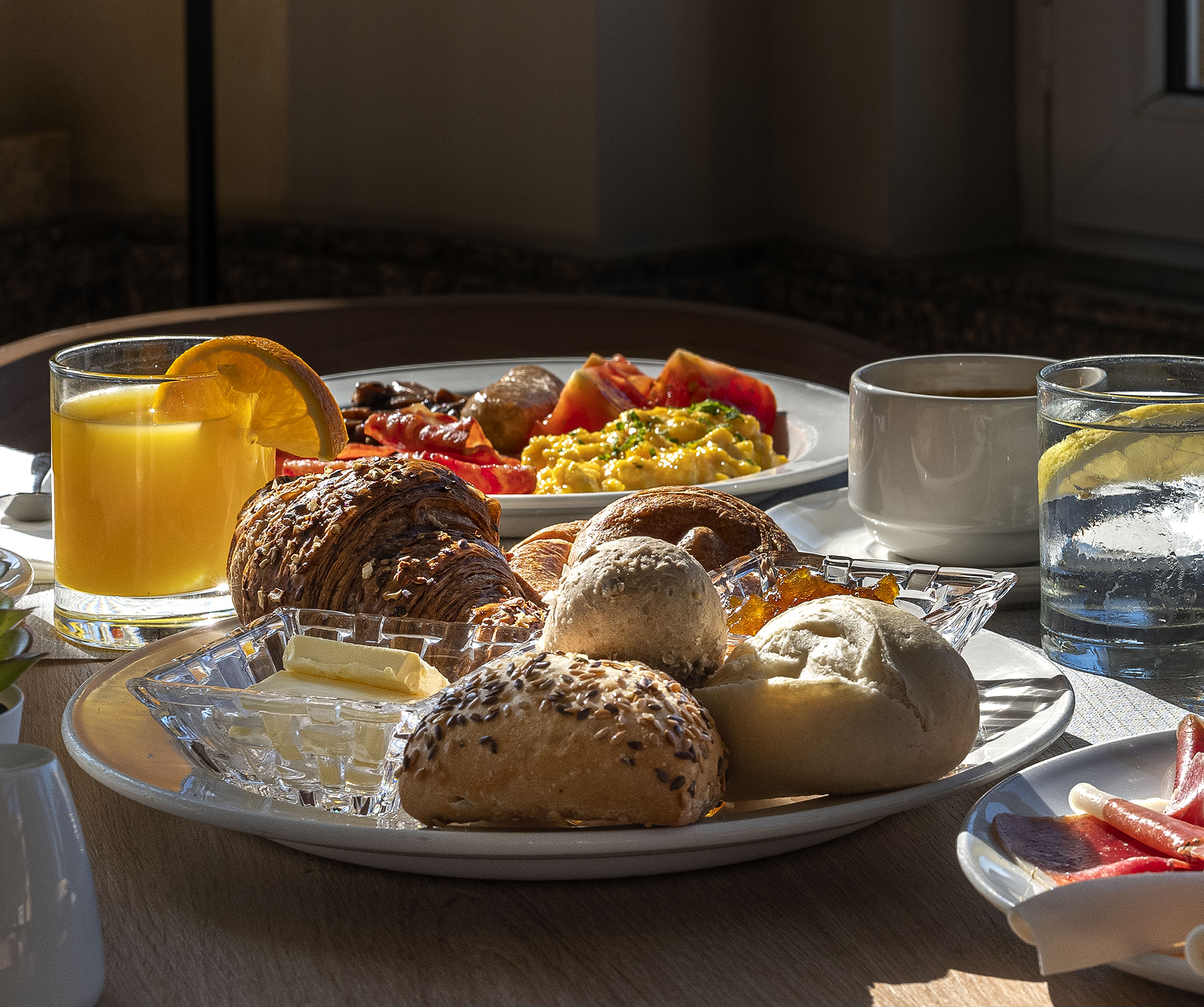 Breakfast with croissant, rolls, orange juice, coffee, eggs, and ham.