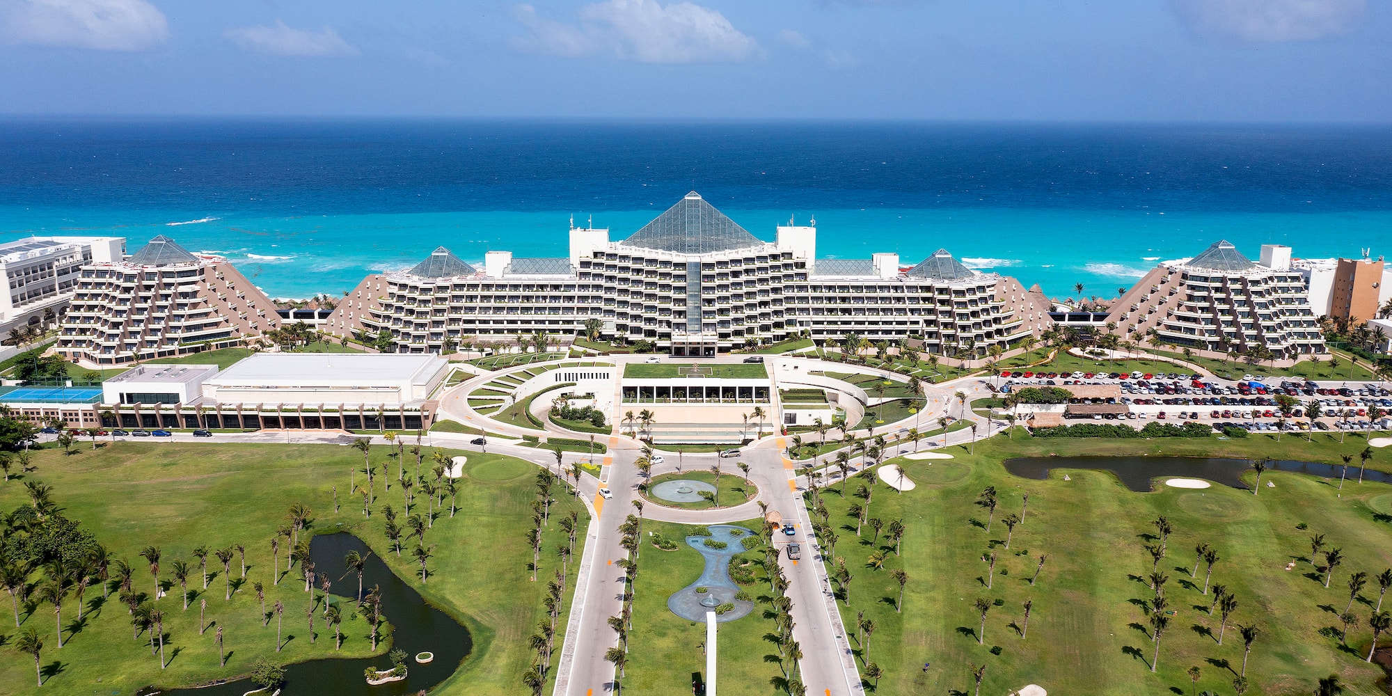 a large building with a pool and a body of water with Fontainebleau Miami Beach in the background