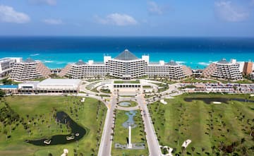 a large building with a pool and a body of water with Fontainebleau Miami Beach in the background