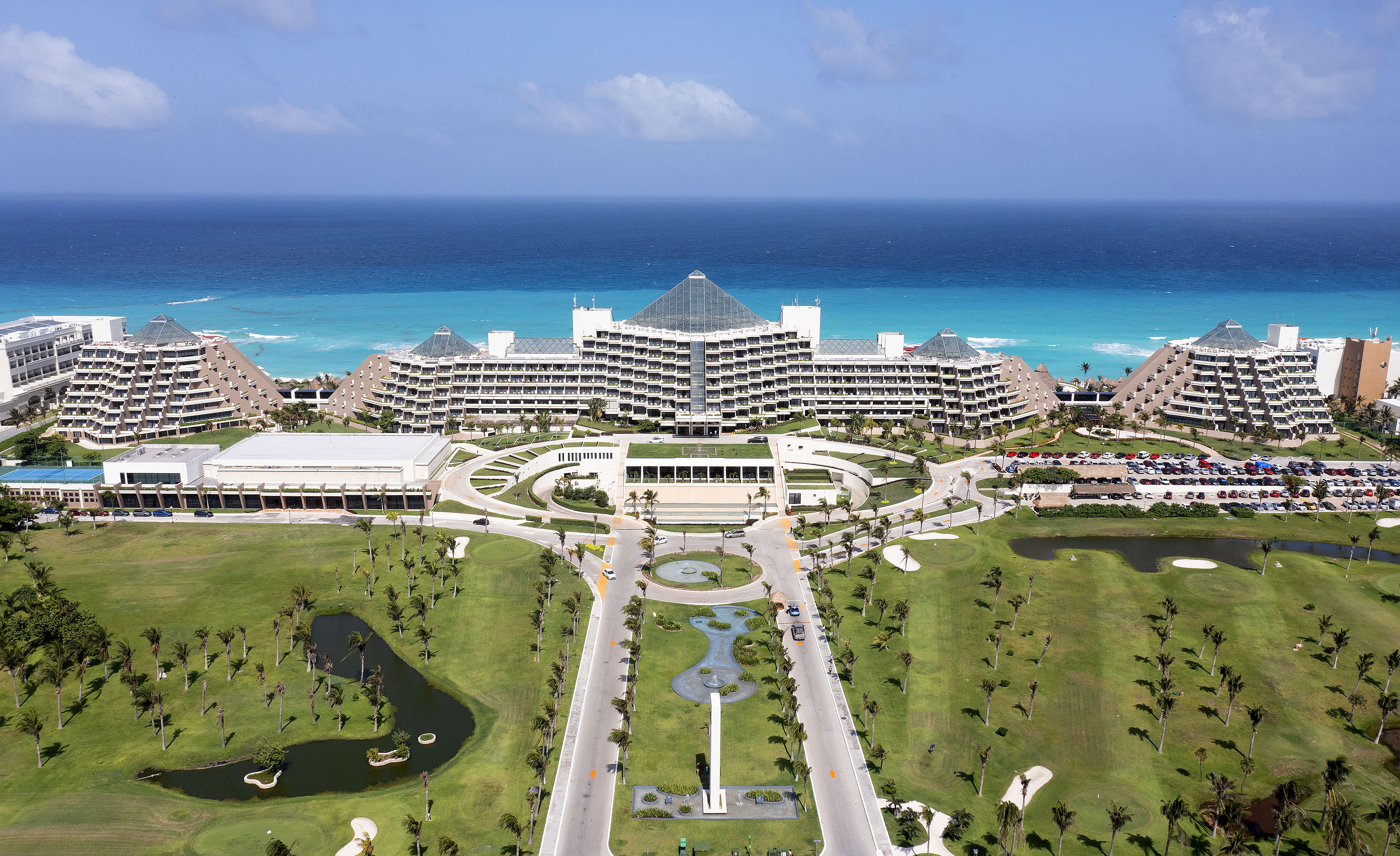 a large building with a pool and a body of water with Fontainebleau Miami Beach in the background