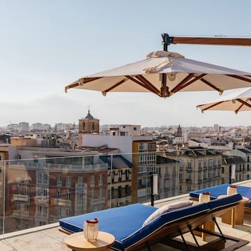 a deck chairs and umbrellas on a rooftop overlooking a city
