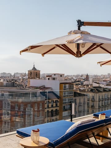 a deck chairs and umbrellas on a rooftop overlooking a city
