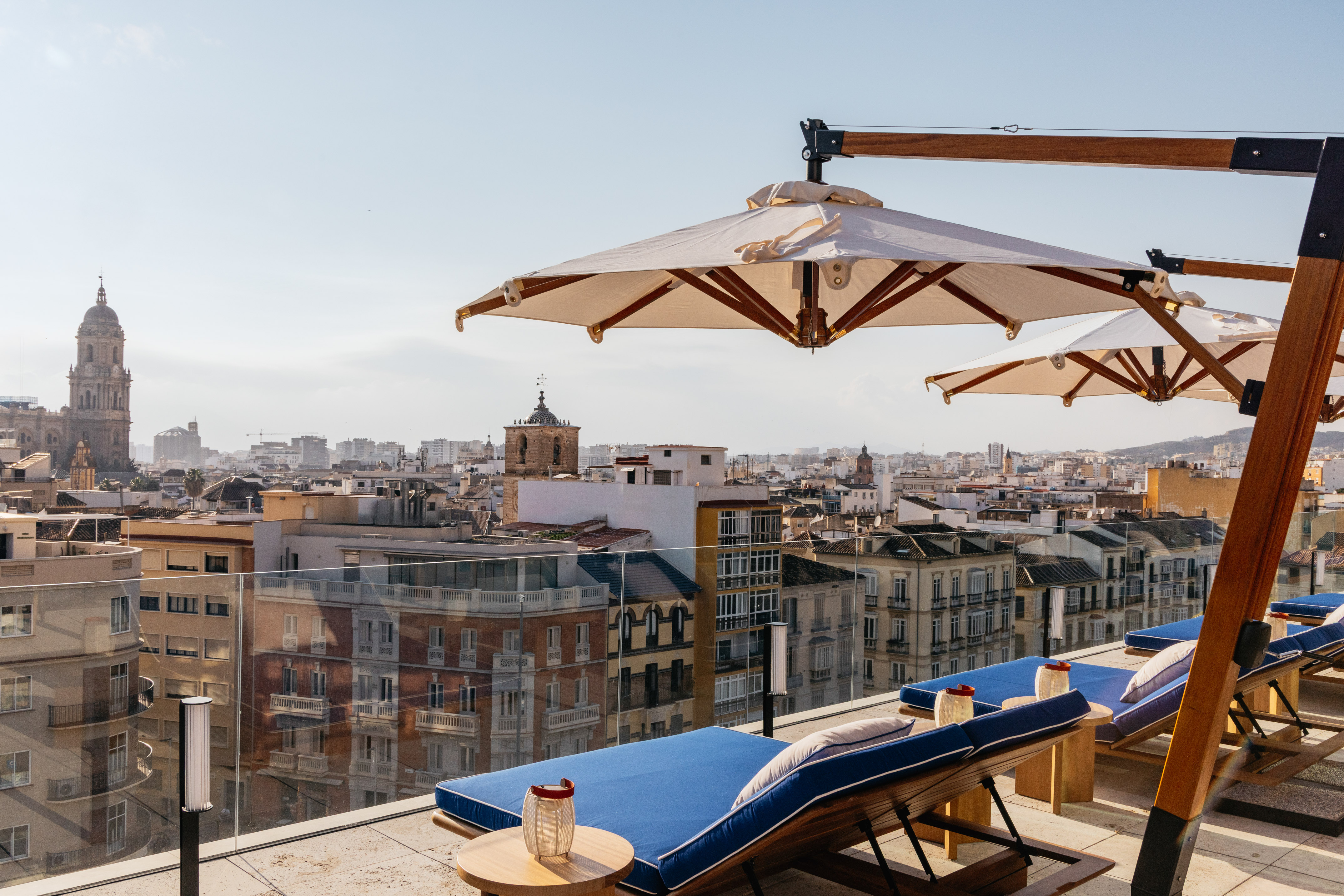 a deck chairs and umbrellas on a rooftop overlooking a city