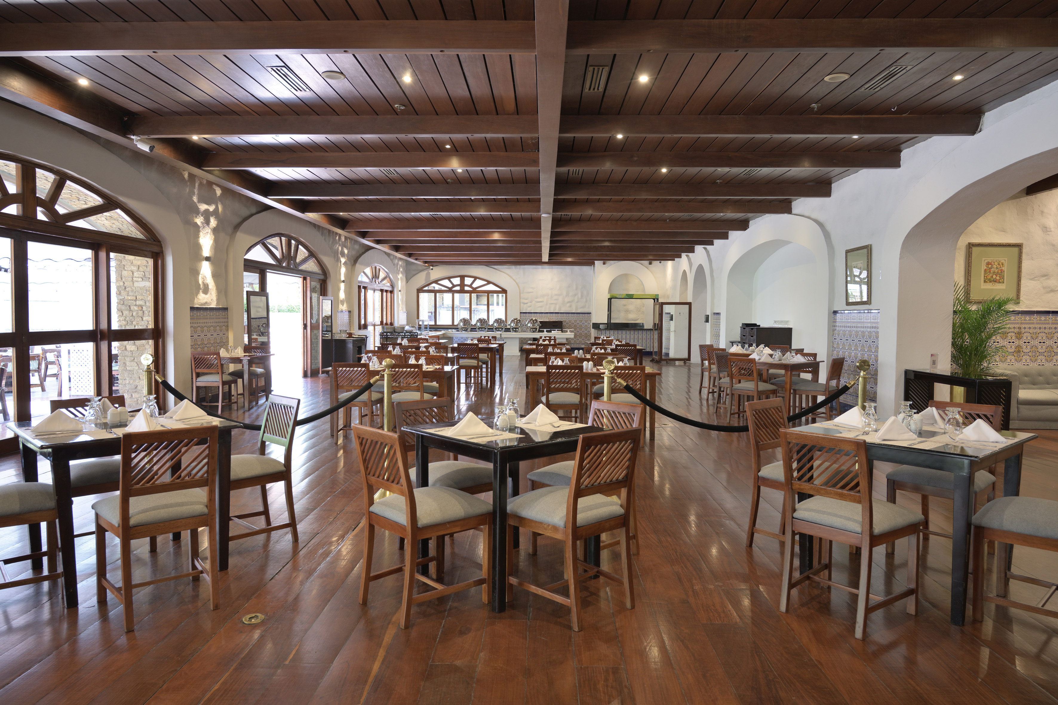 Hotel restaurant with wooden floors, beamed ceiling, set tables, buffet.