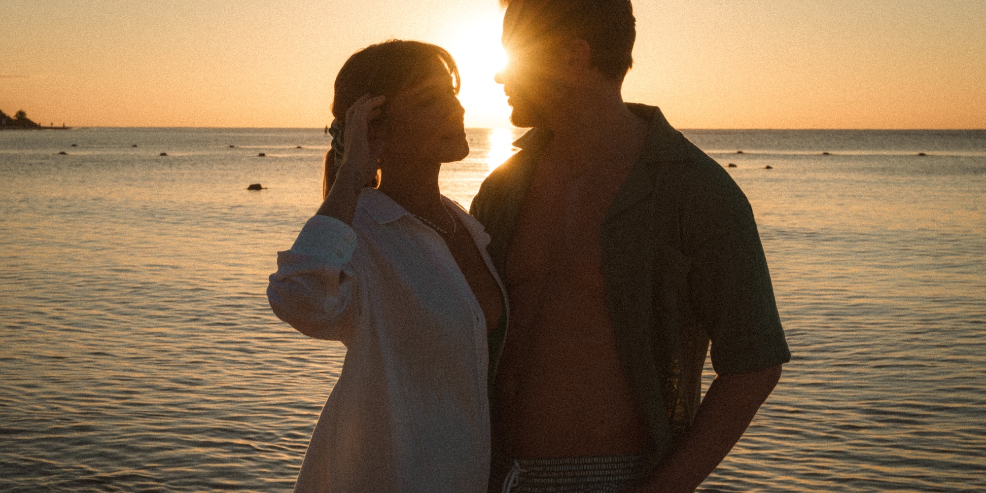a man and woman standing next to each other in front of water