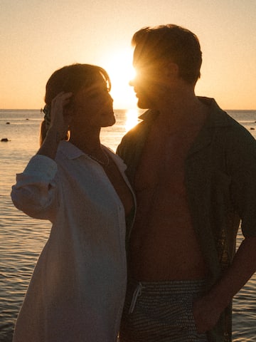 a man and woman standing next to each other in front of water