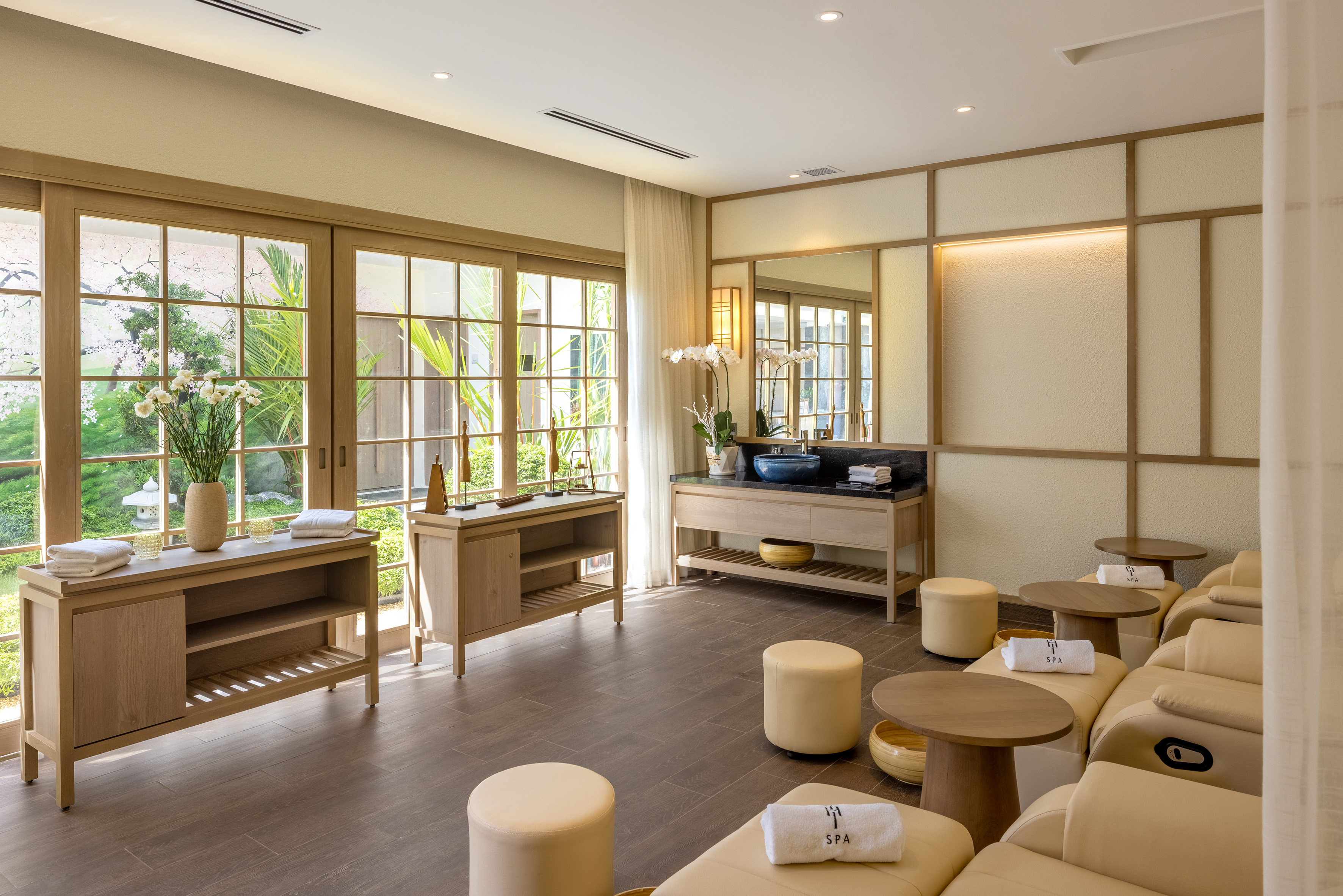 Modern foot spa lounge with recliners, wooden consoles, and garden view.