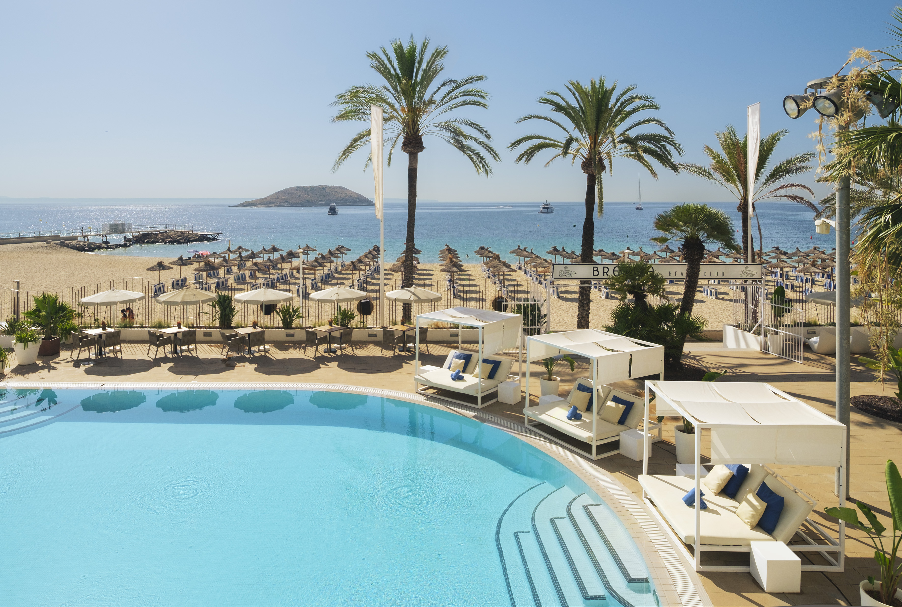 a pool with lounge chairs and umbrellas on a beach