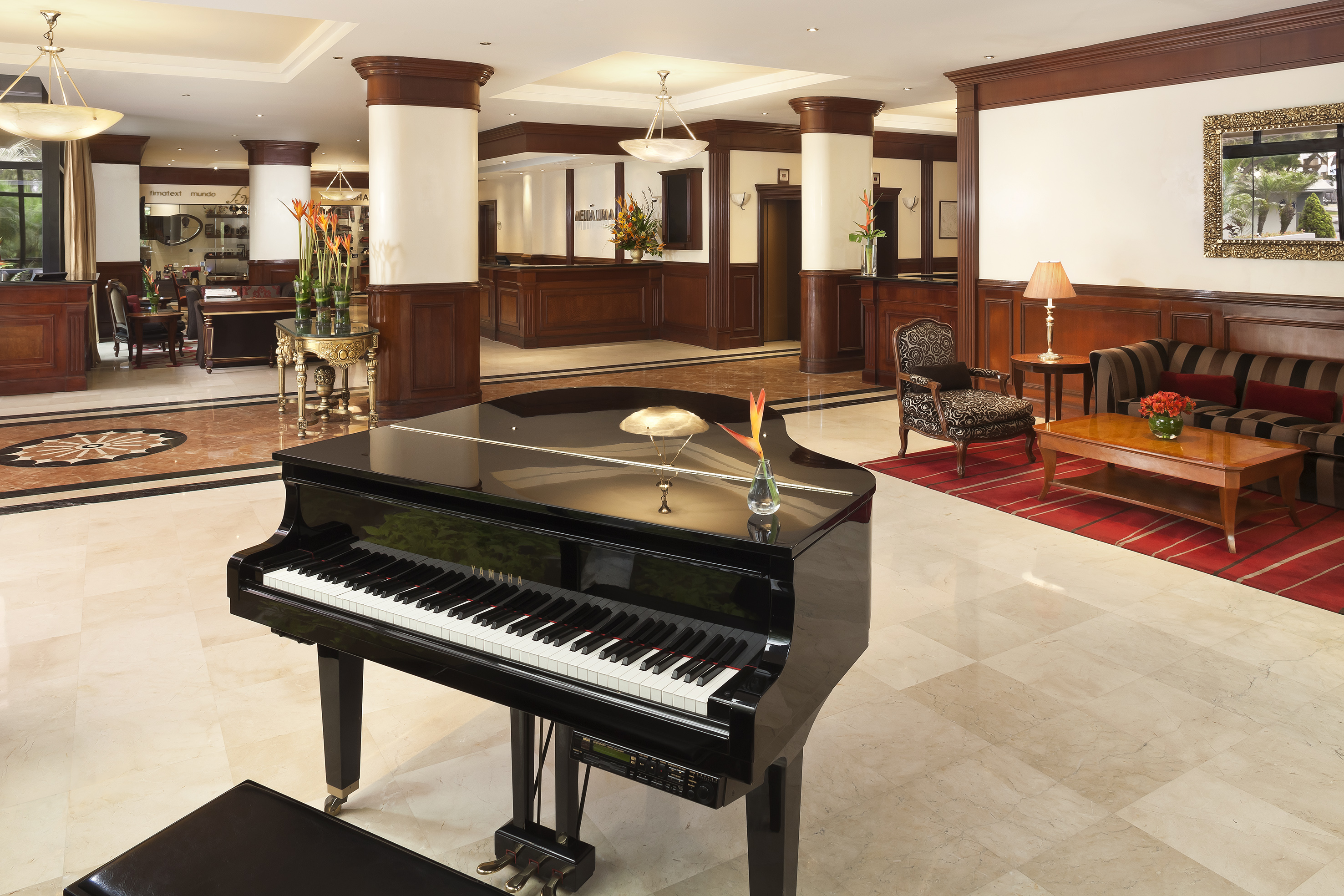 Luxurious hotel lobby with a black grand piano, reception, and elegant lounge.