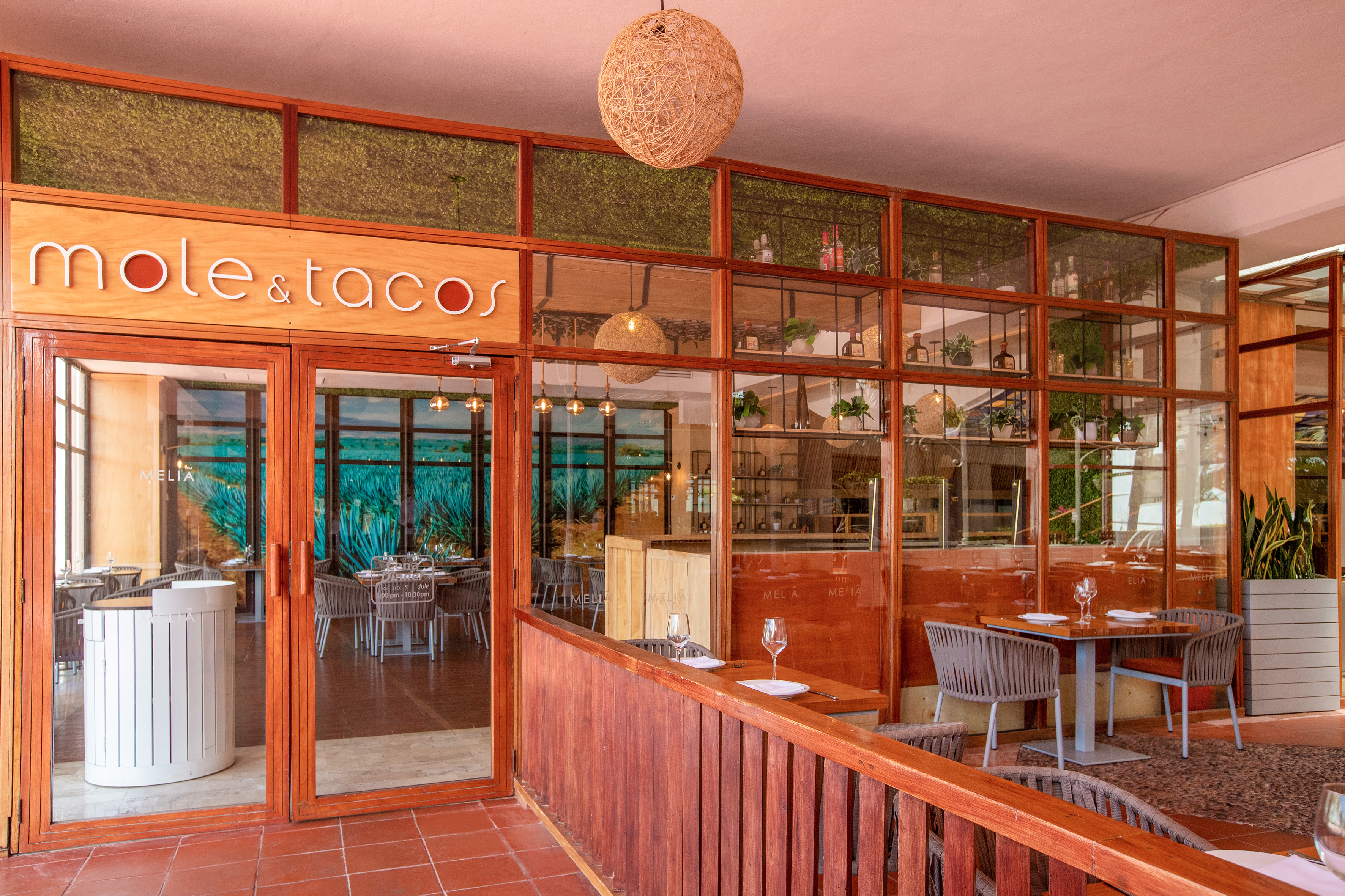 Mole & Tacos restaurant exterior: wood, glass, outdoor seating. Meliá.