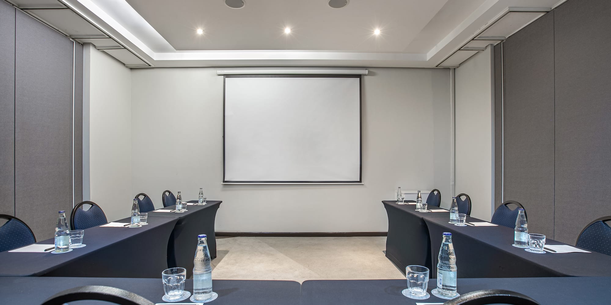 a room with tables and chairs and a projector screen
