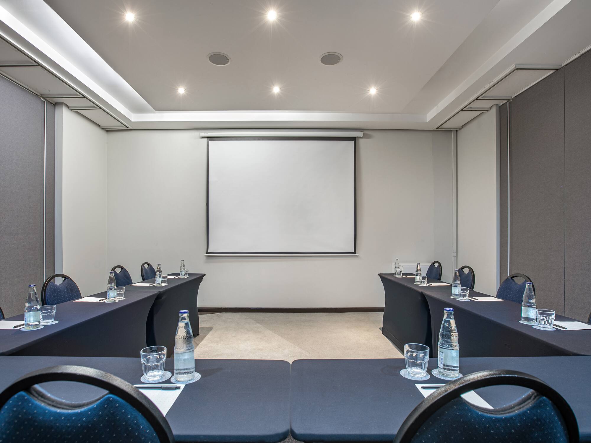 a room with tables and chairs and a projector screen