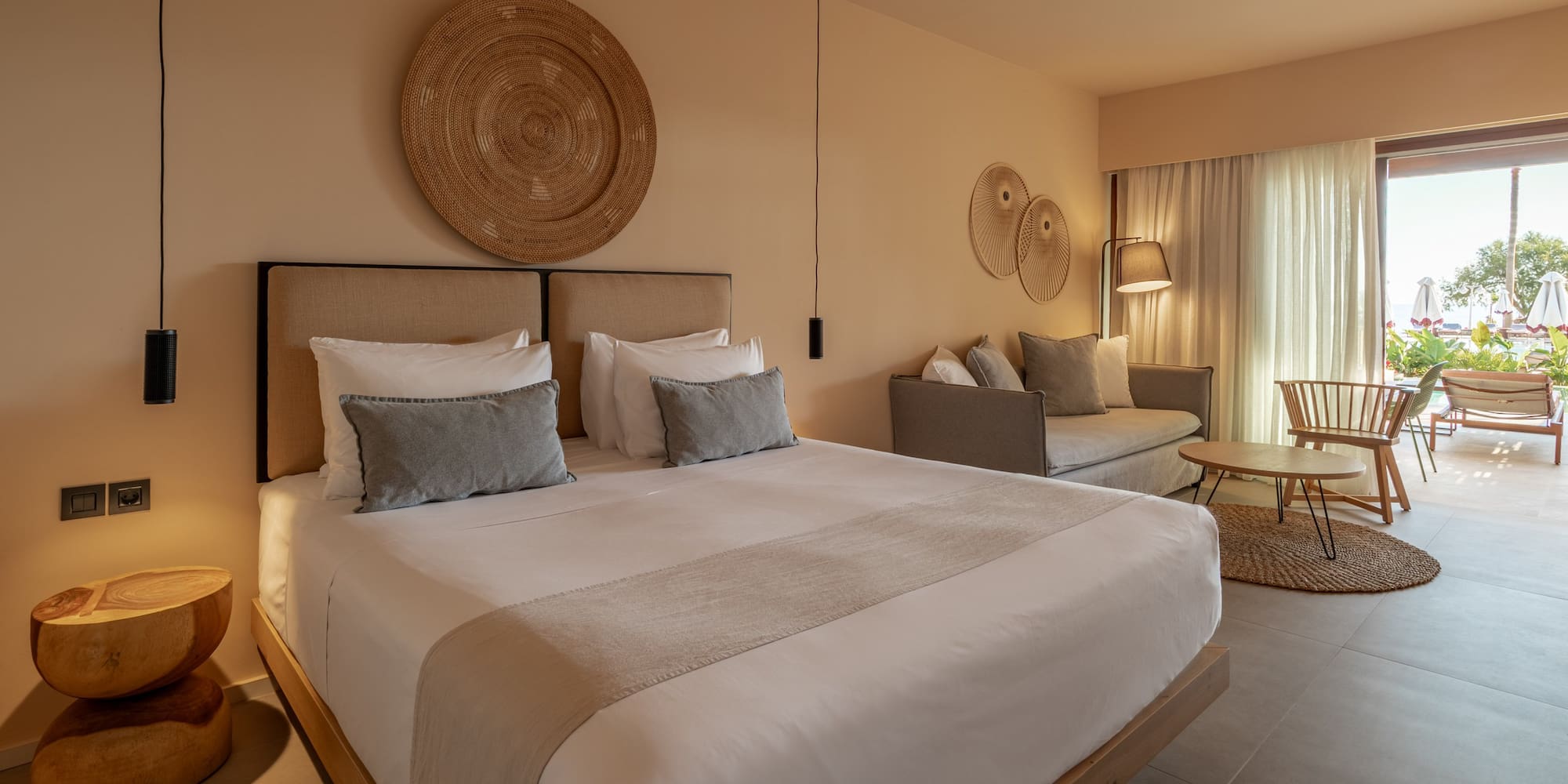Elegant hotel suite with king bed, neutral tones, and bright patio view.