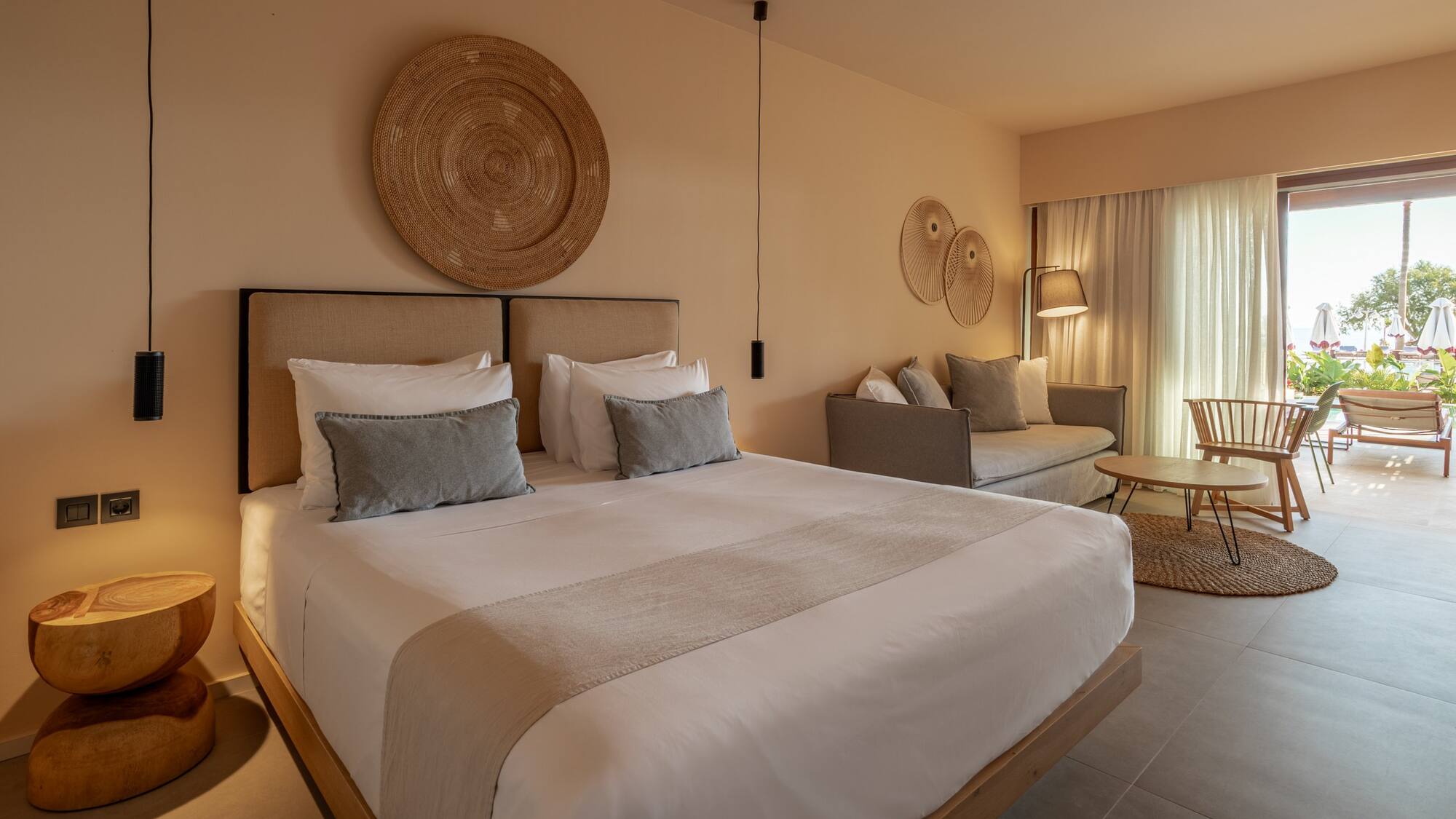 Elegant hotel suite with king bed, neutral tones, and bright patio view.