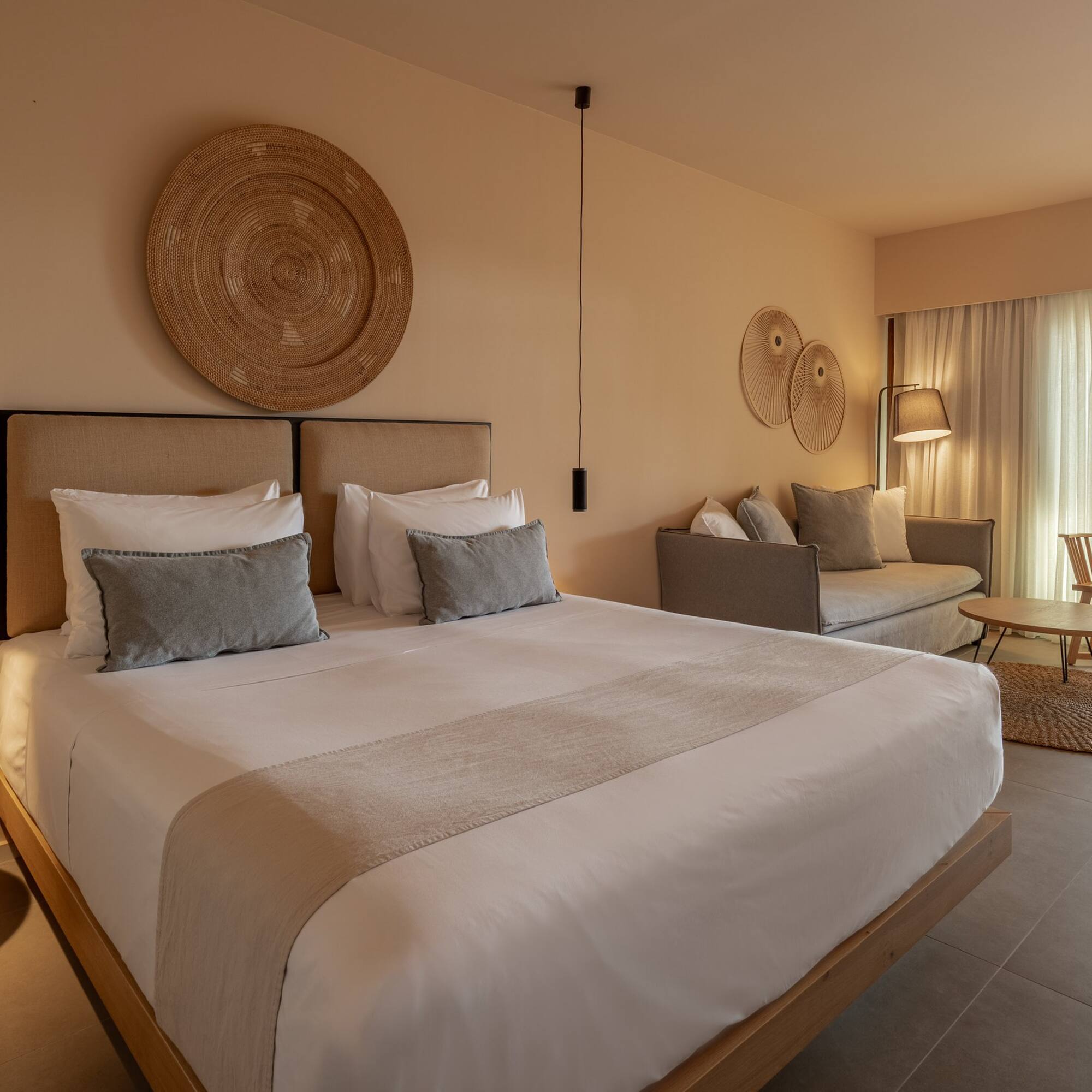Elegant hotel suite with king bed, neutral tones, and bright patio view.