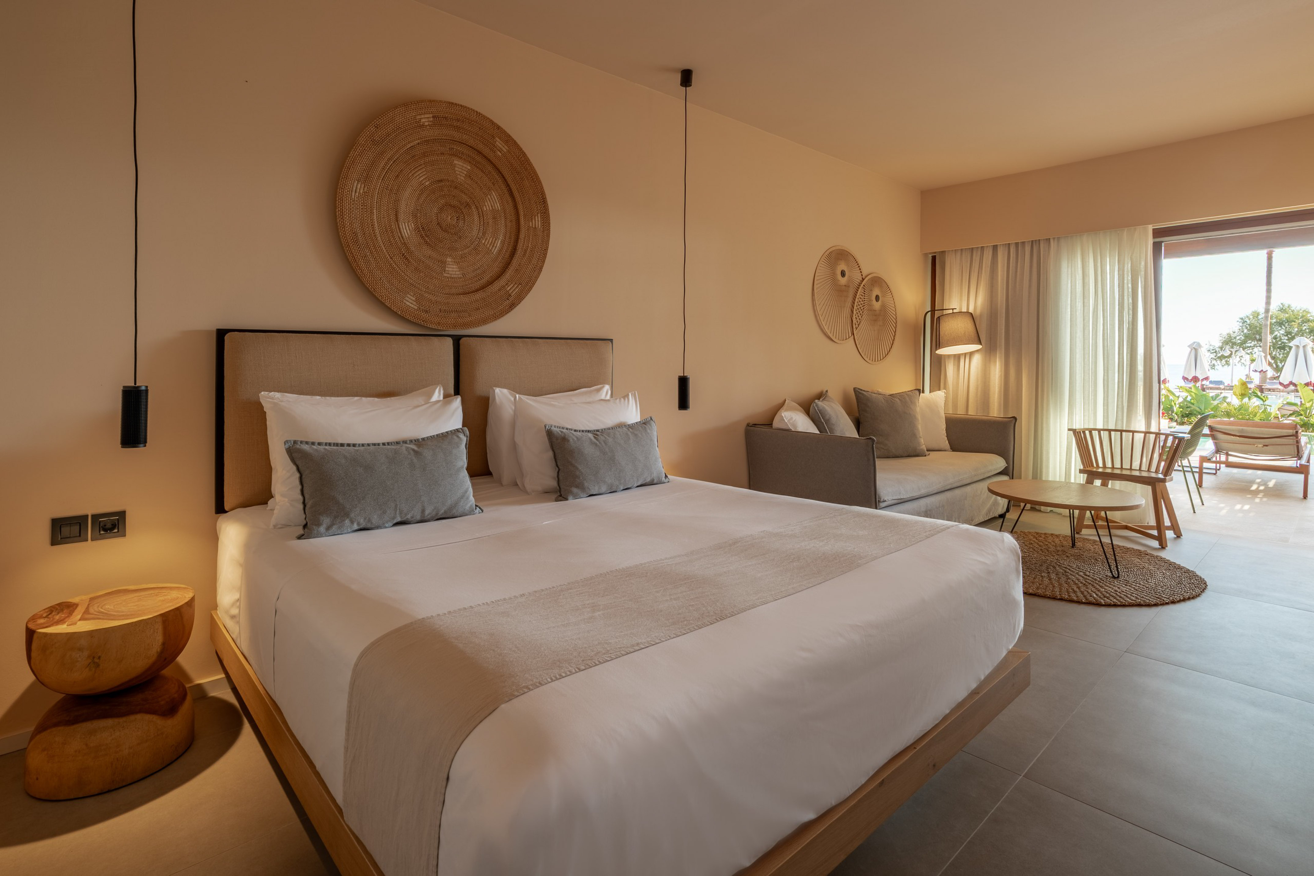 Elegant hotel suite with king bed, neutral tones, and bright patio view.