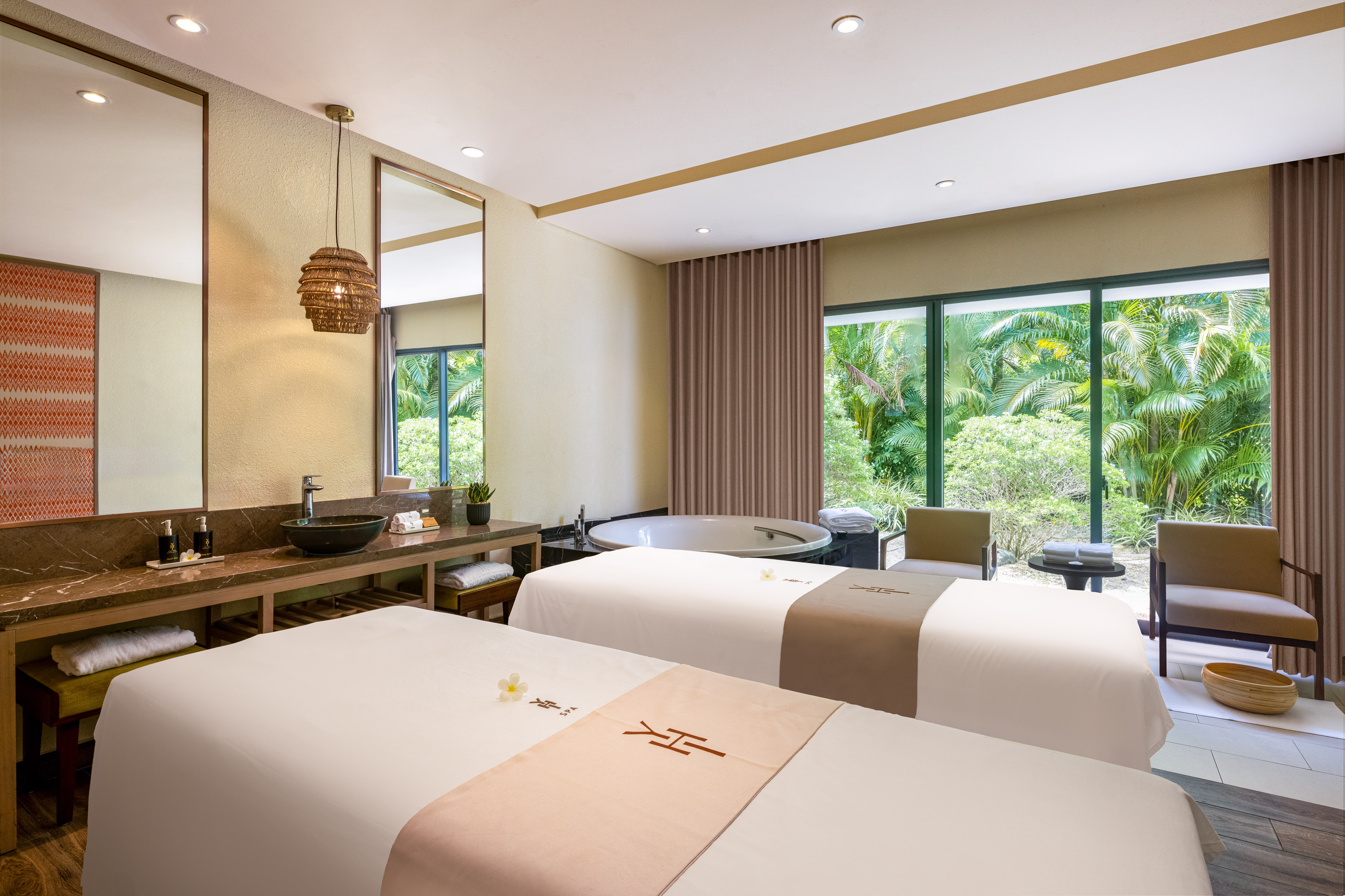 Serene spa treatment room with dual massage beds, soaking tub, and tropical view.
