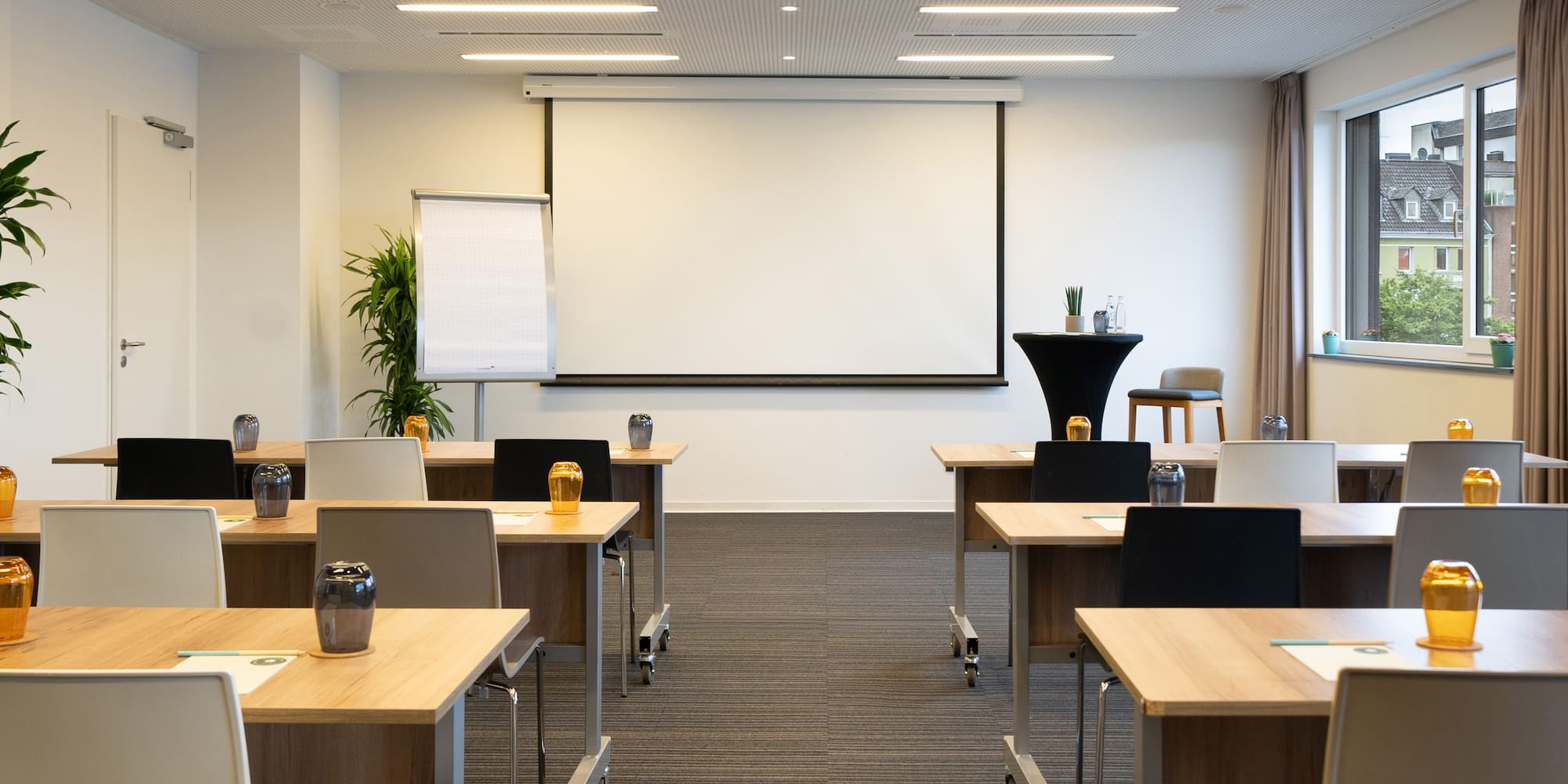 a room with tables and chairs and a projector screen