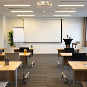 a room with tables and chairs and a projector screen