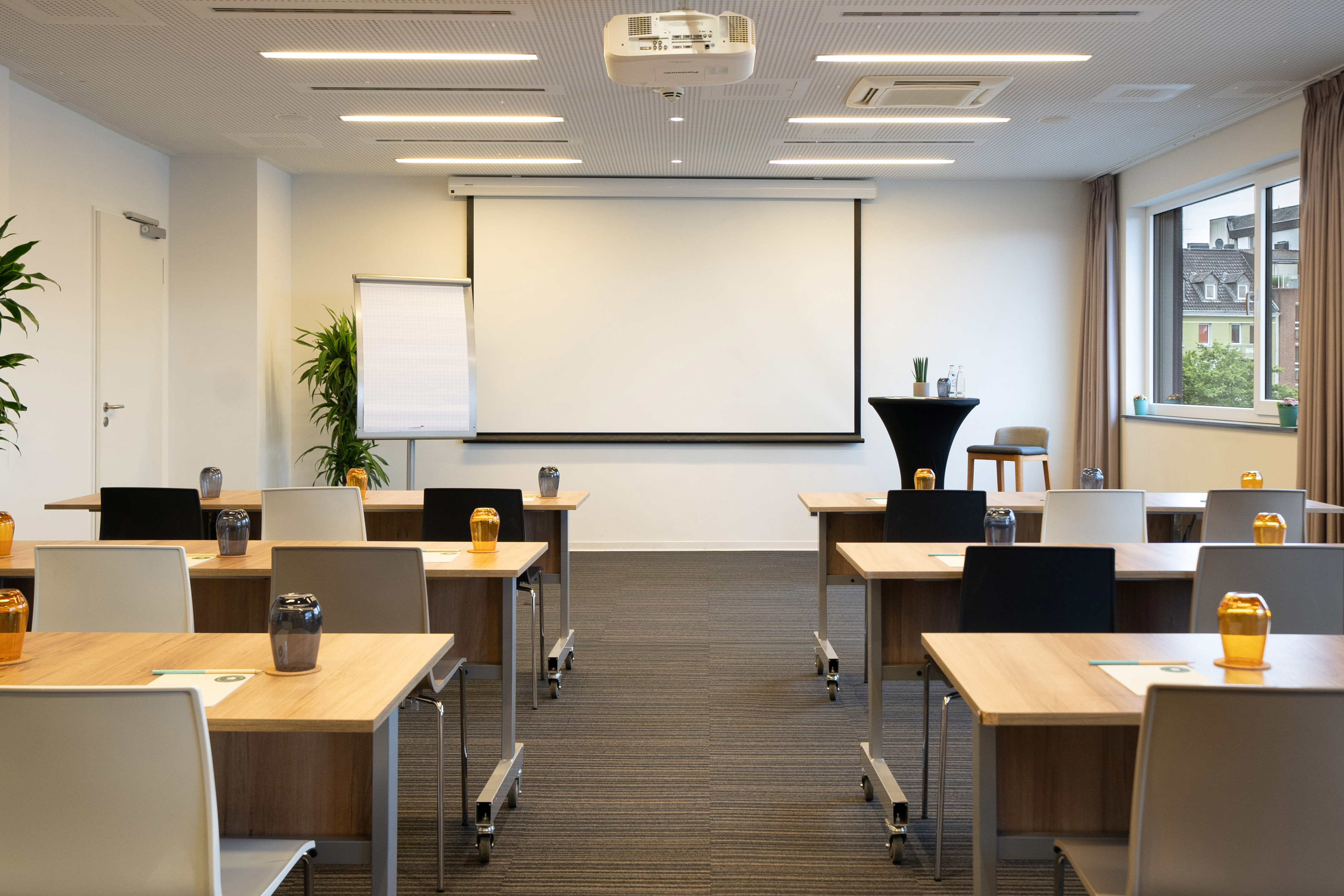 Conference room with projector screen, flexible tables, and chairs.