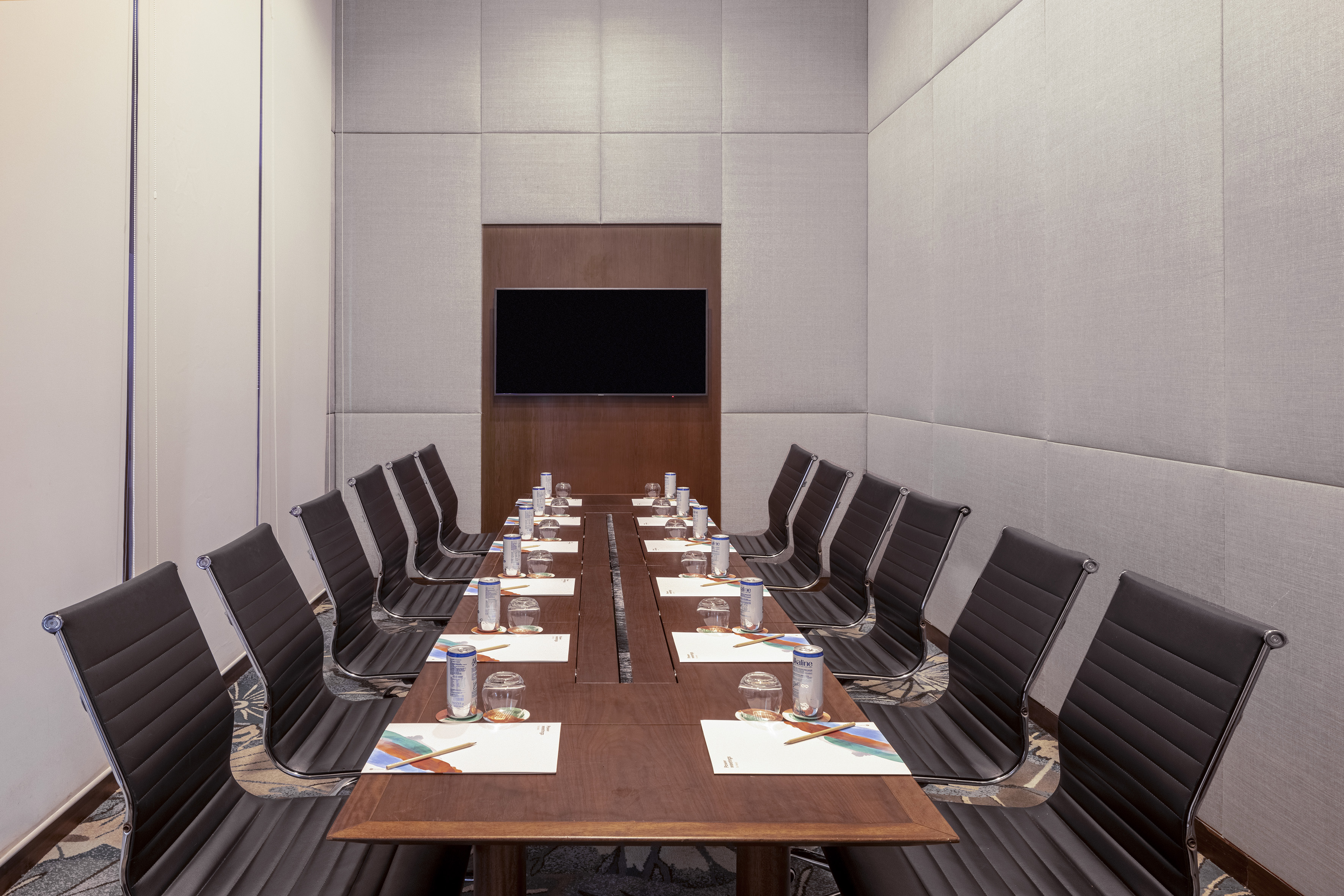 Professional meeting room with long table, executive chairs, and TV display.