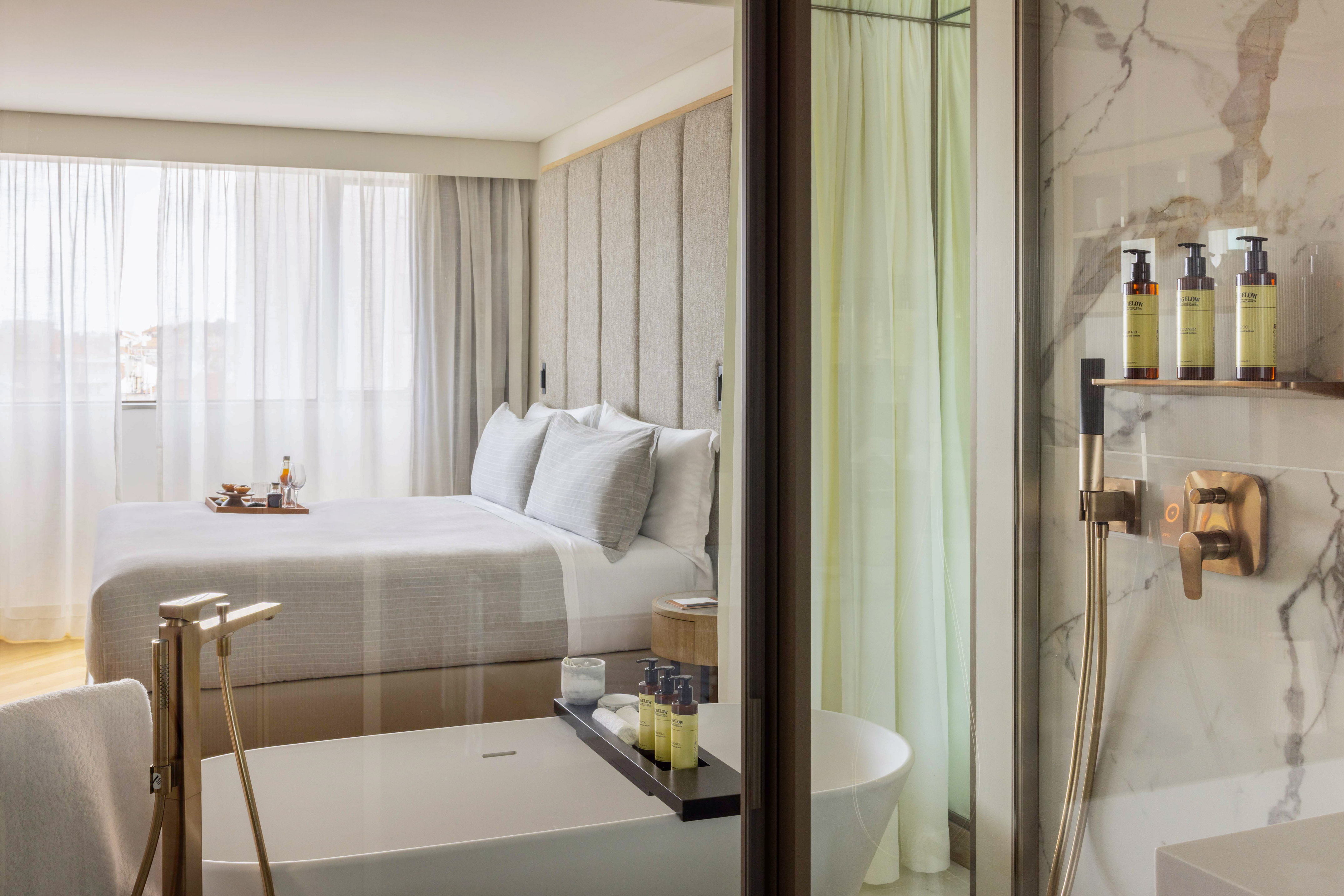 Modern hotel bedroom and open bath with luxurious freestanding tub.